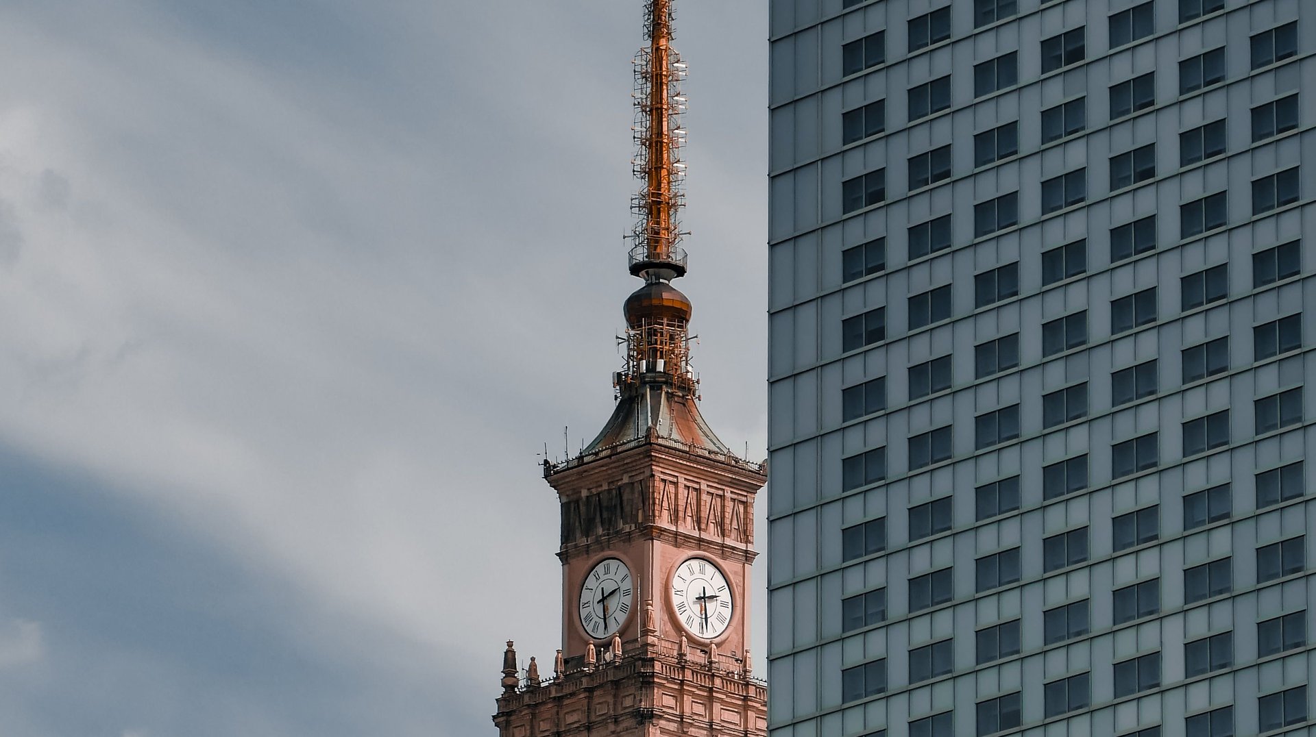 Vertical View of Warsaw's Iconic Palace of Culture and Science Clock Tower Against Modern Architecture.