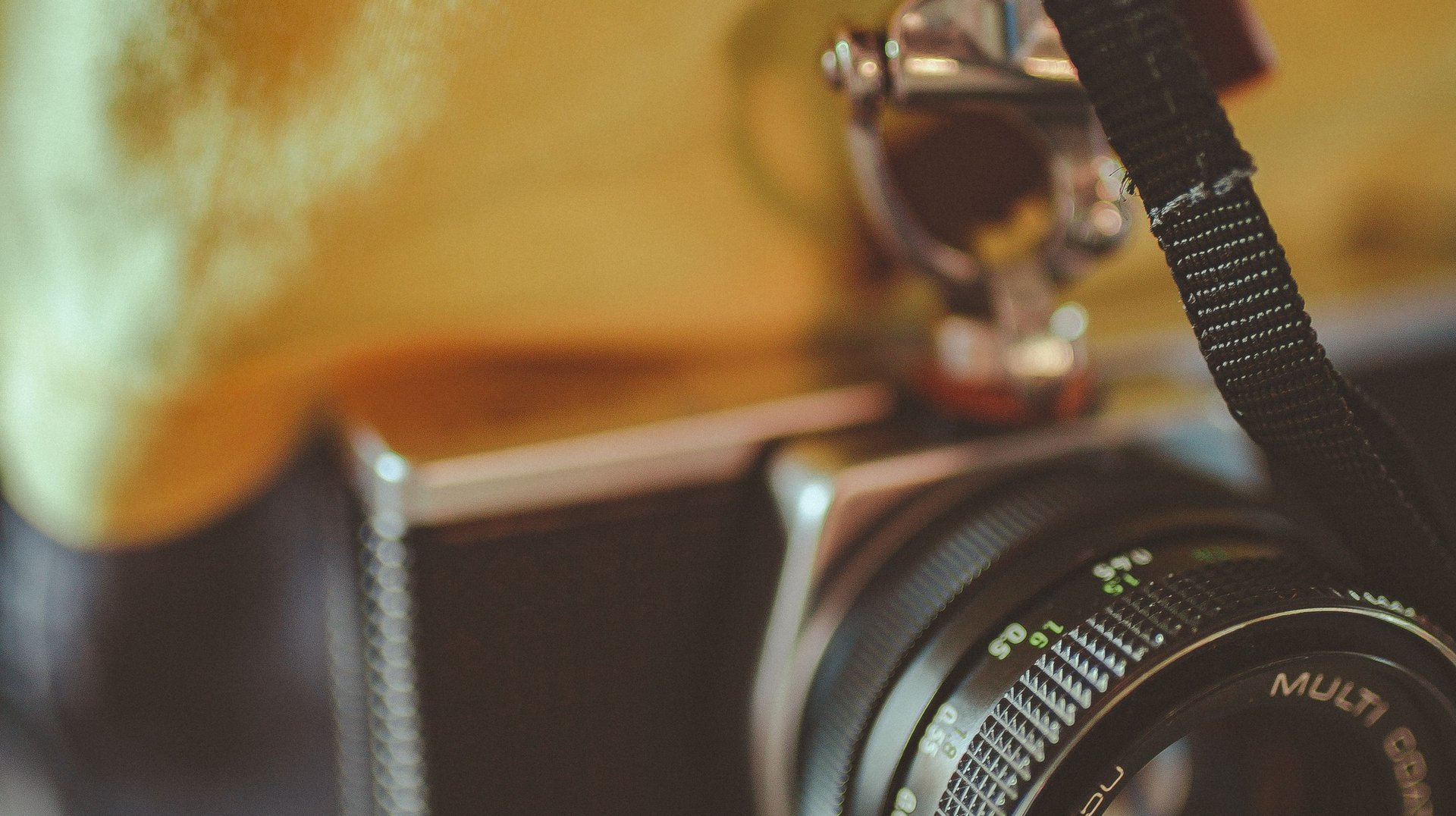 Close-up of an Old Vintage Camera Hanging by Its Strap, Focused on the Lens.
