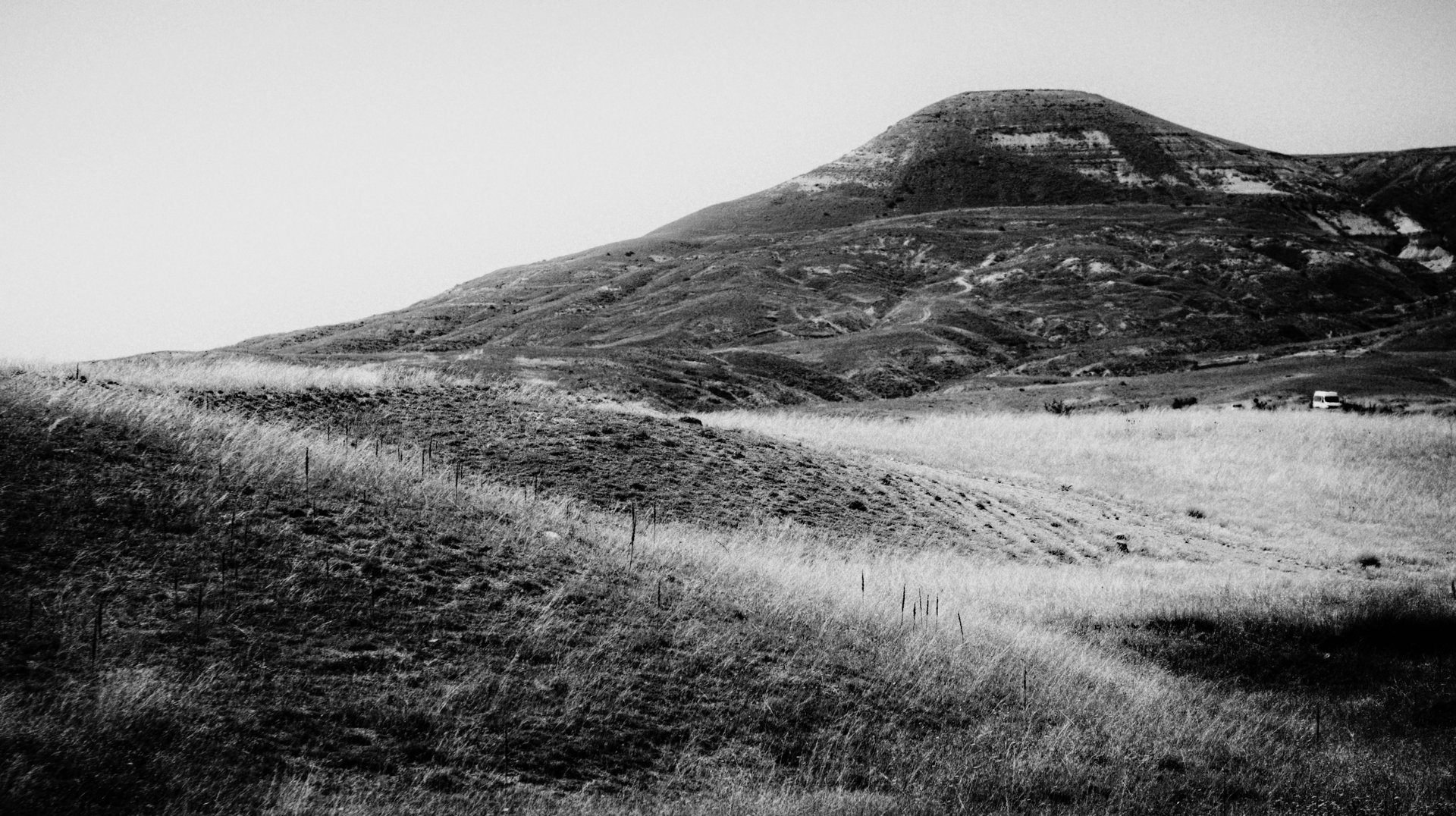 Dramatic Black and White Image of Serene Rolling Hills and a Distant Mountain.