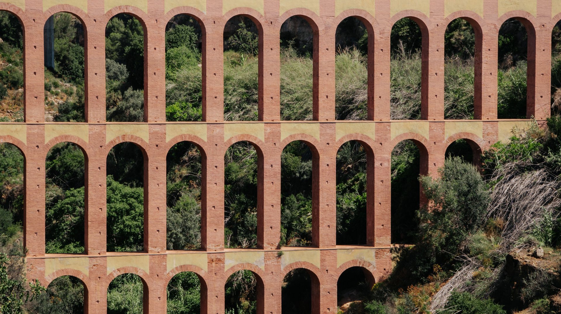 a Breathtaking View of the Iconic Eagle Aqueduct in Nerja, Surrounded by Lush Greenery and Mountains.