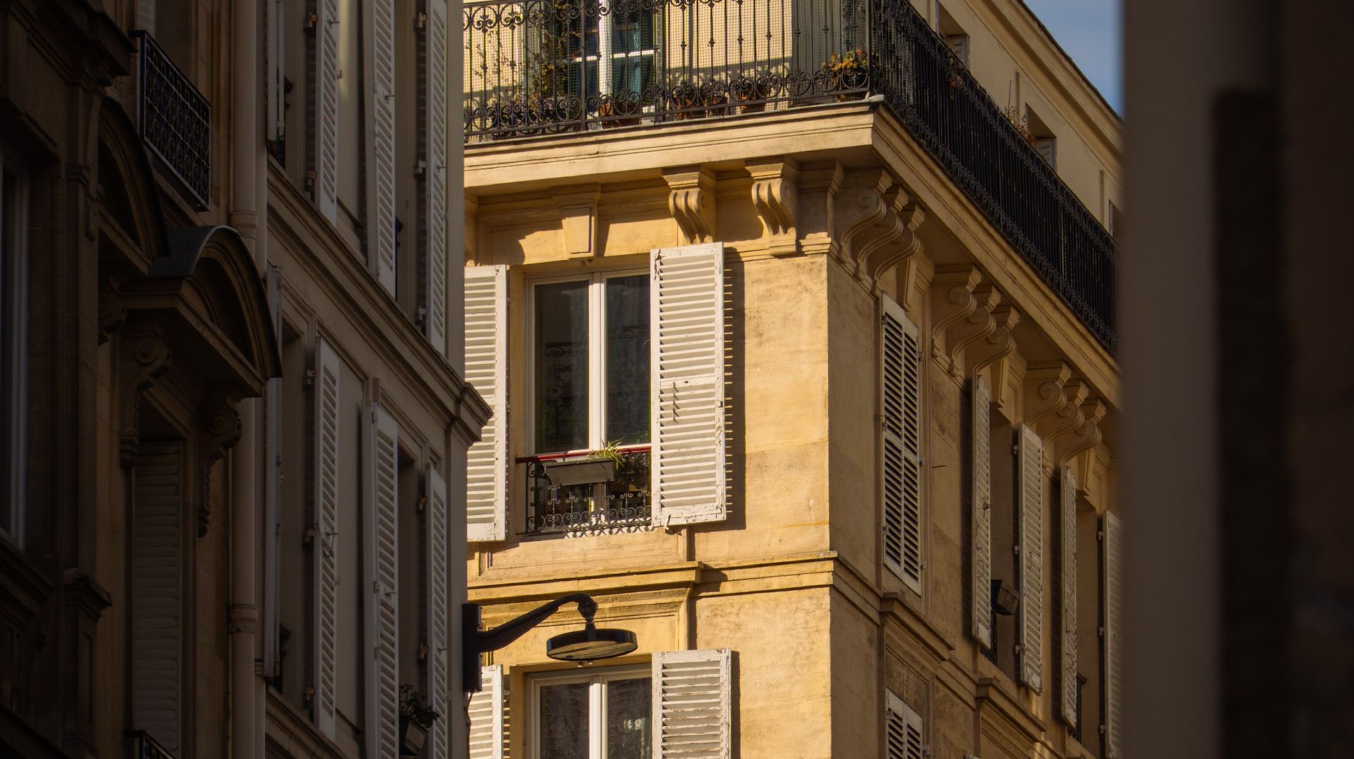 a Sunlit Street Scene Featuring Classic Parisian Architecture with Traditional Shutters and Balconies.