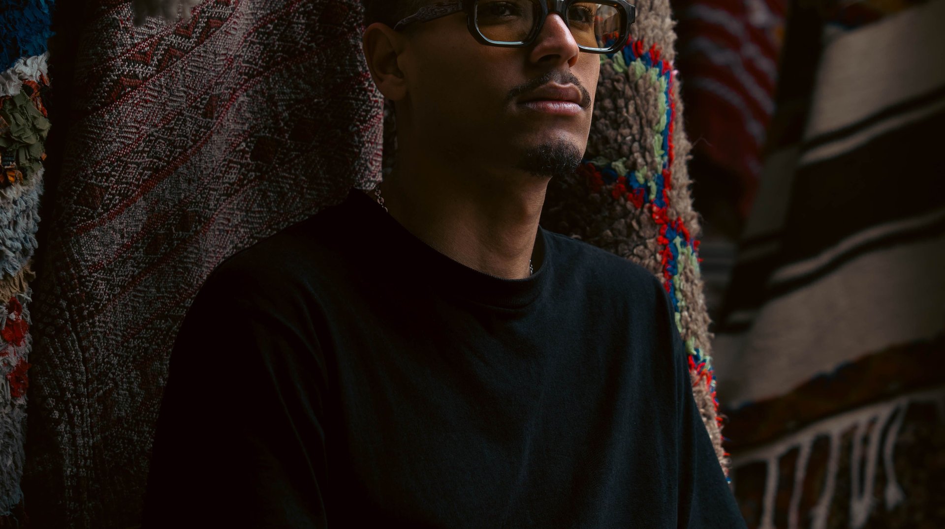 a Man Sits Thoughtfully Amidst Vibrant Moroccan Textiles in Casablanca.