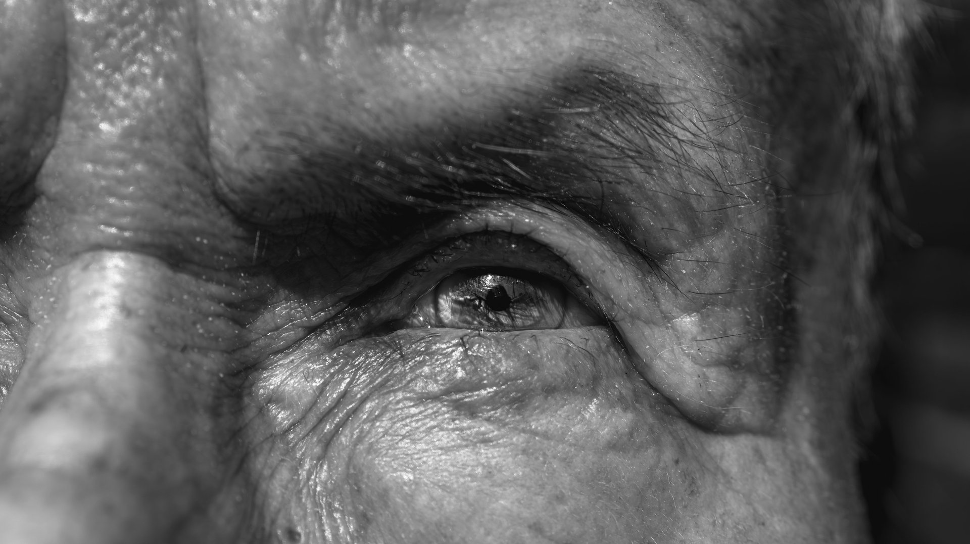 Detailed Black and White Close-up of an Elderly Man's Eye, Capturing Texture and Emotion.