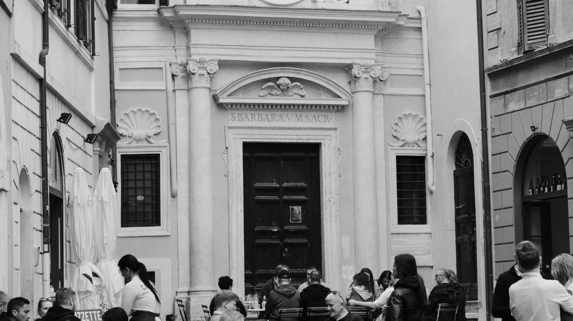 Lively Street Cafe Scene in Rome, Italy with Patrons Enjoying Outdoor Dining Near Historic Architecture.