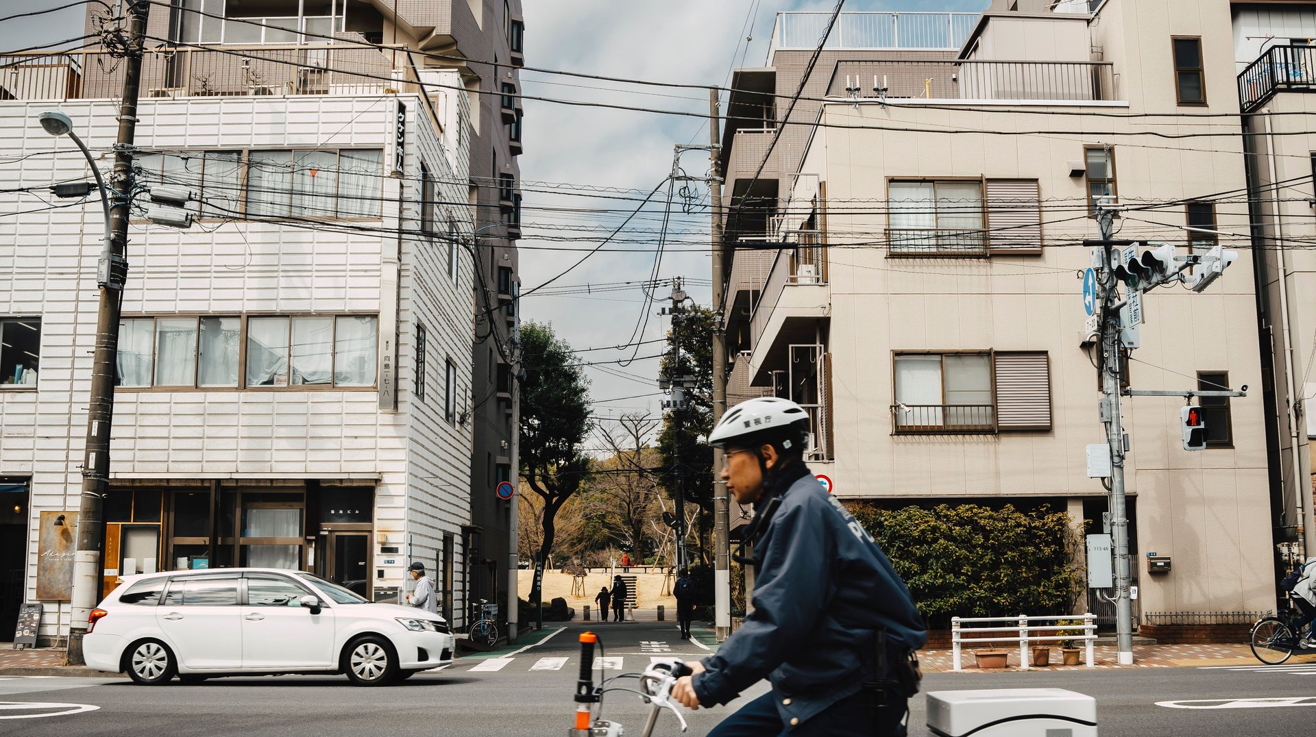 a Bicyclist Crosses an Intersection in Tokyo with Tall Residential Buildings in the Background.