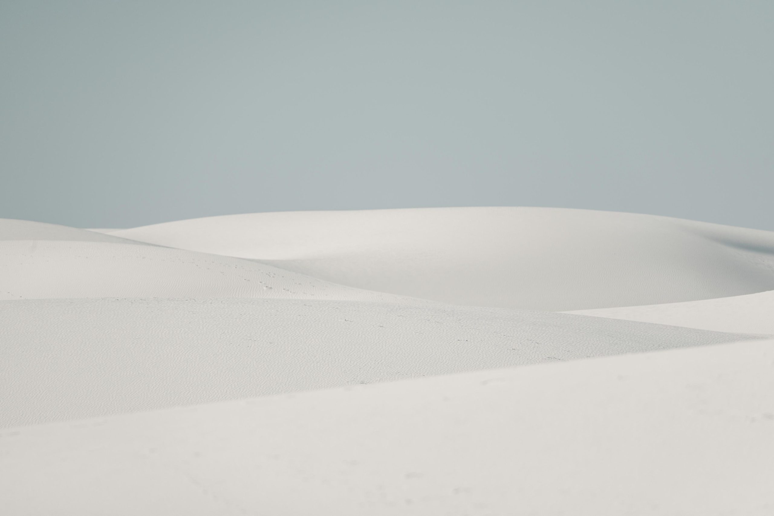 Soft white sand dunes under a pale sky
