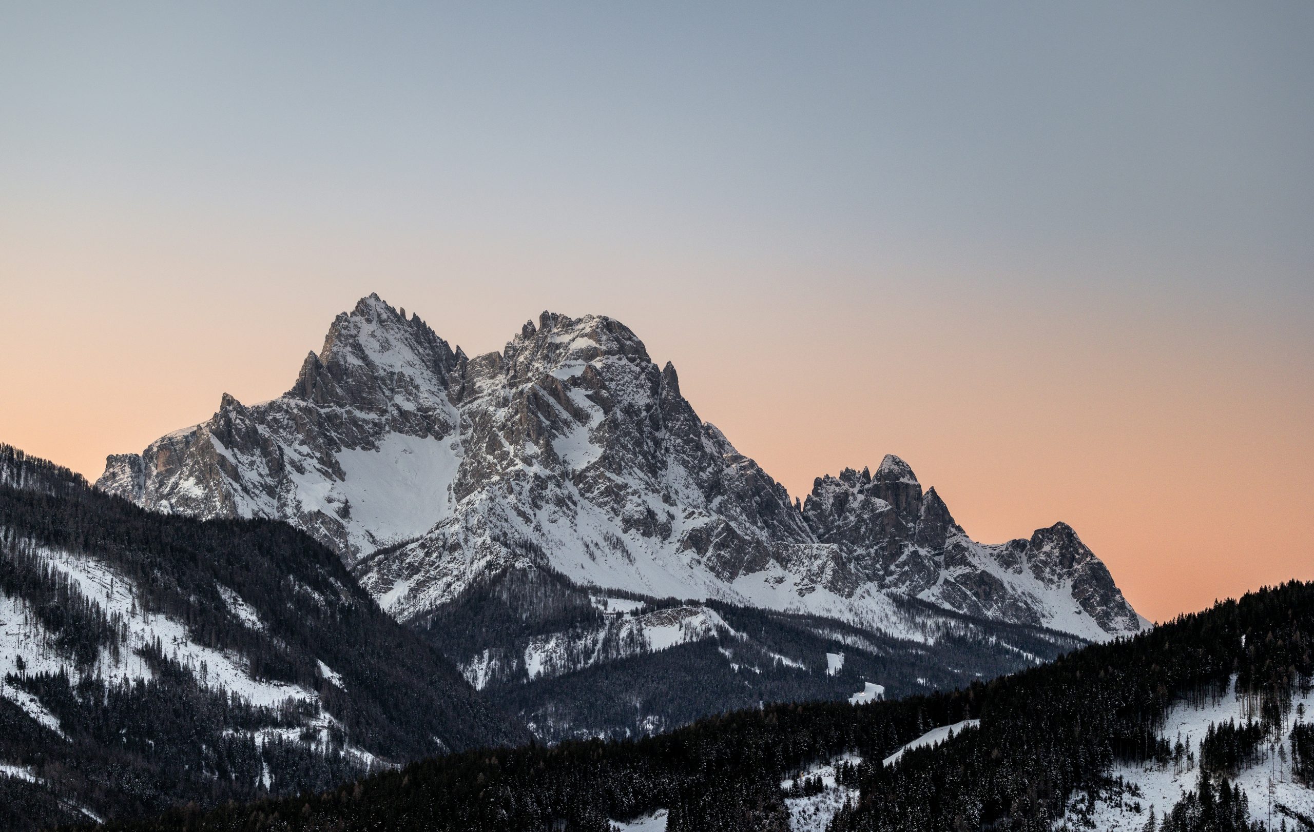 Snow-capped mountain peaks against a pastel sky