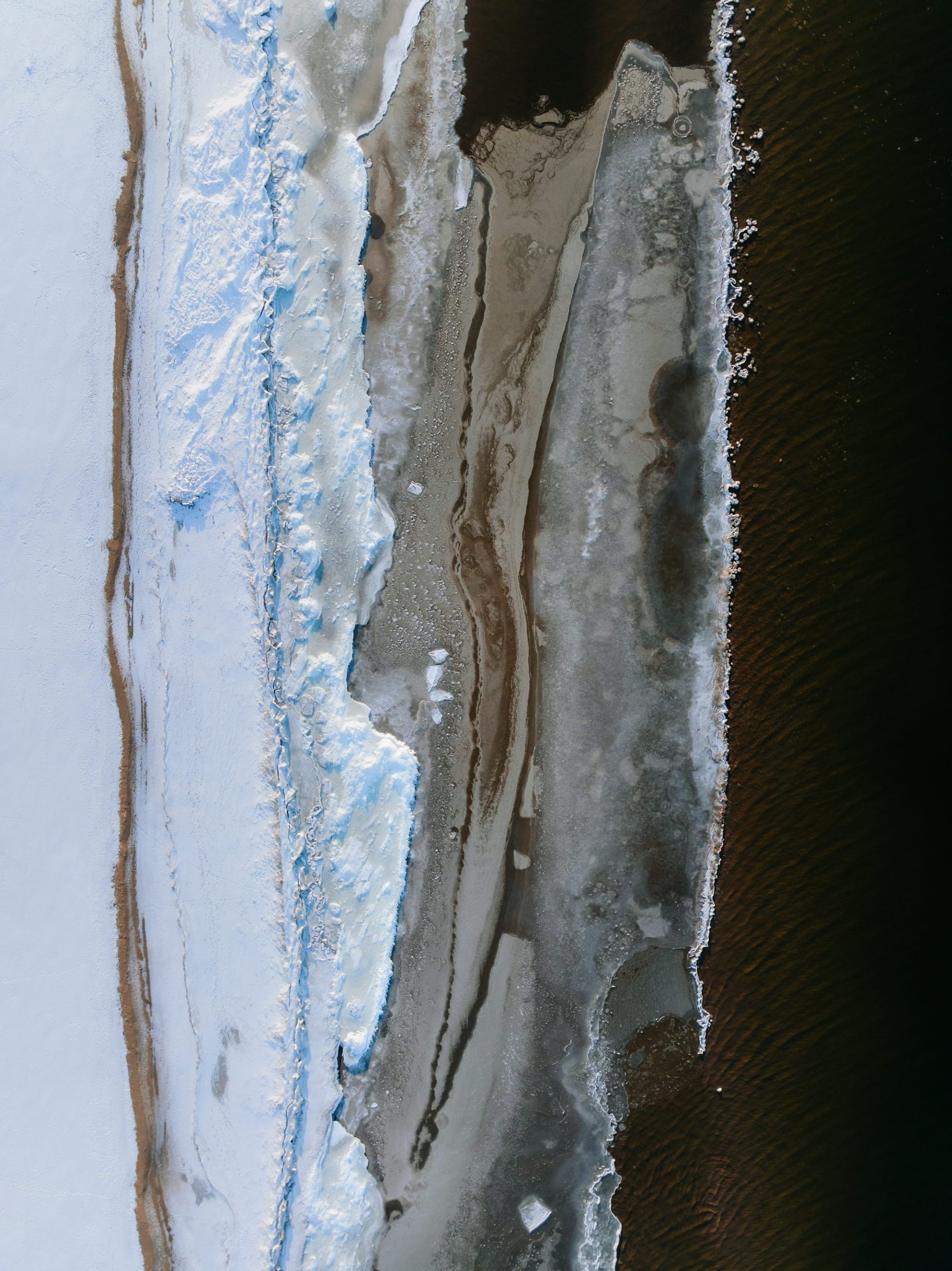 Frozen Riverbank With Dark Water And Ice Formations
