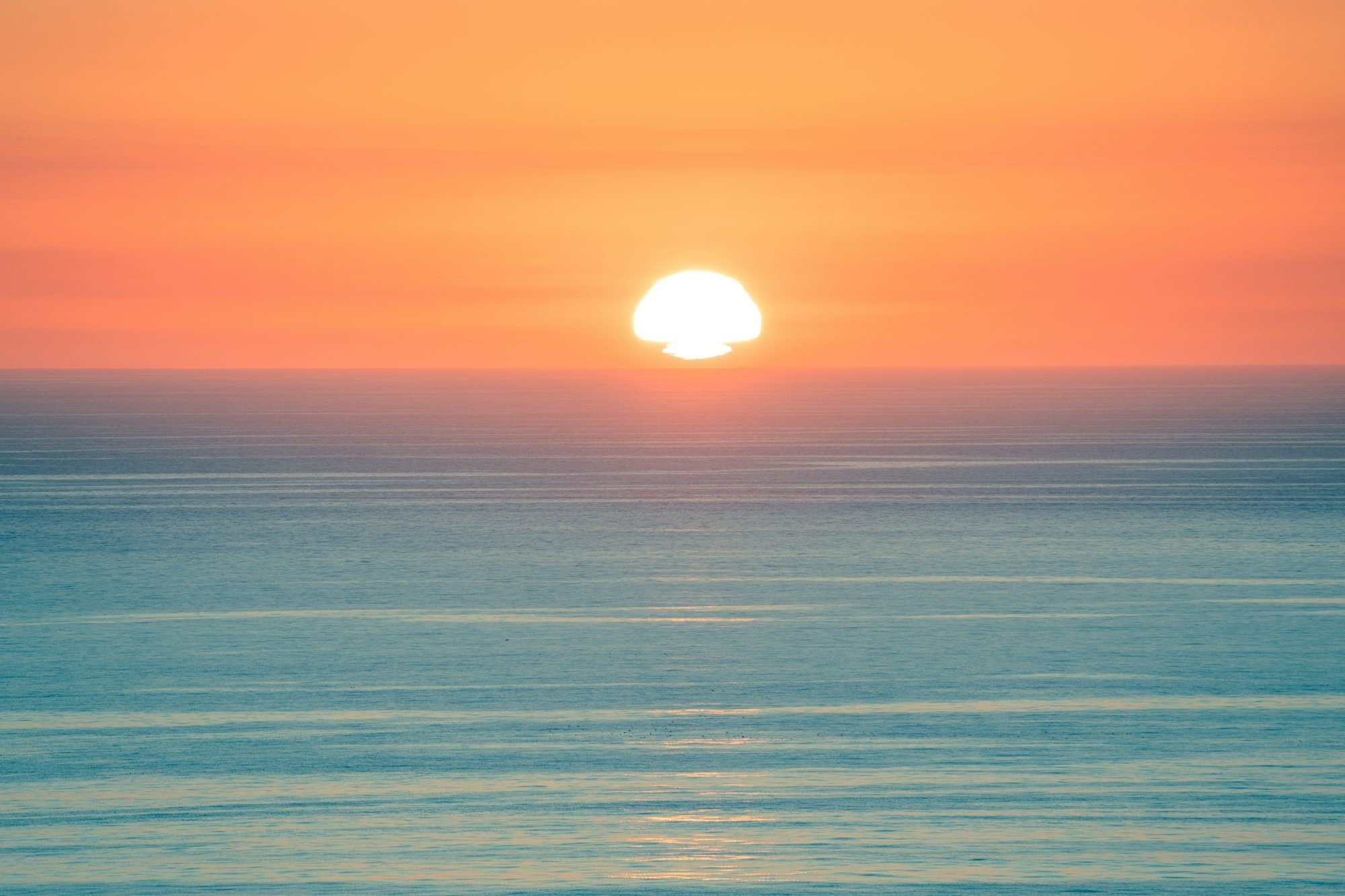 Sun Setting Over A Calm Ocean Horizon