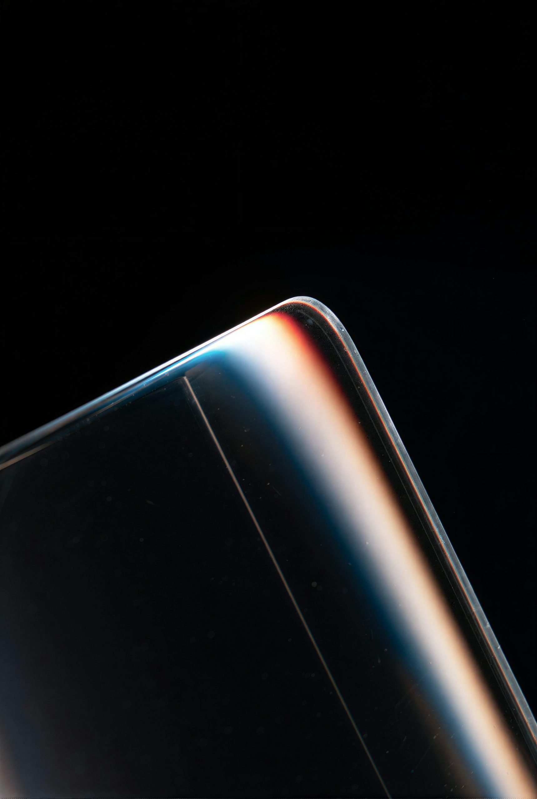 Close-Up Of A Curved Glass Edge With Colorful Light Reflections