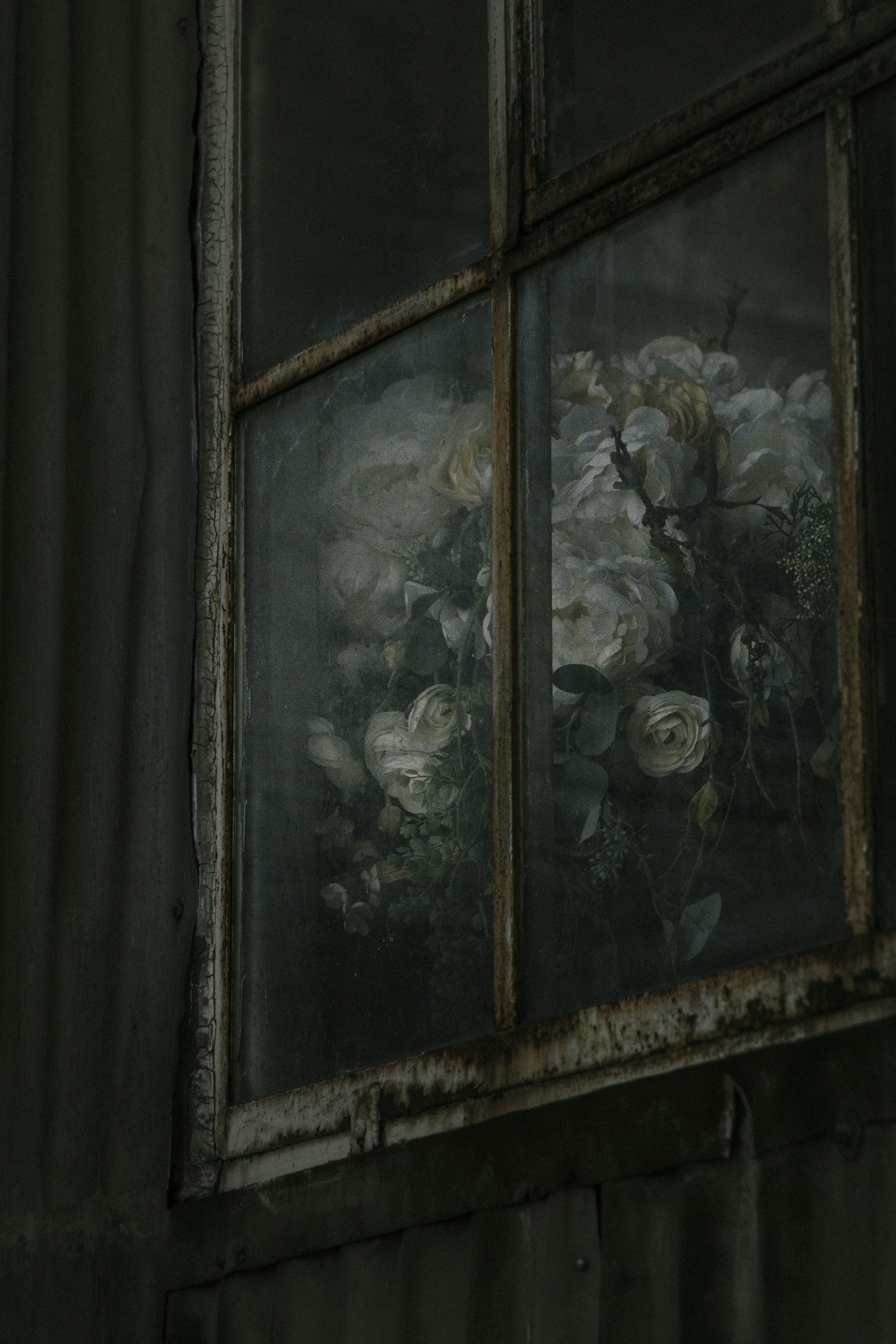 Bouquet of white roses seen through a dusty window