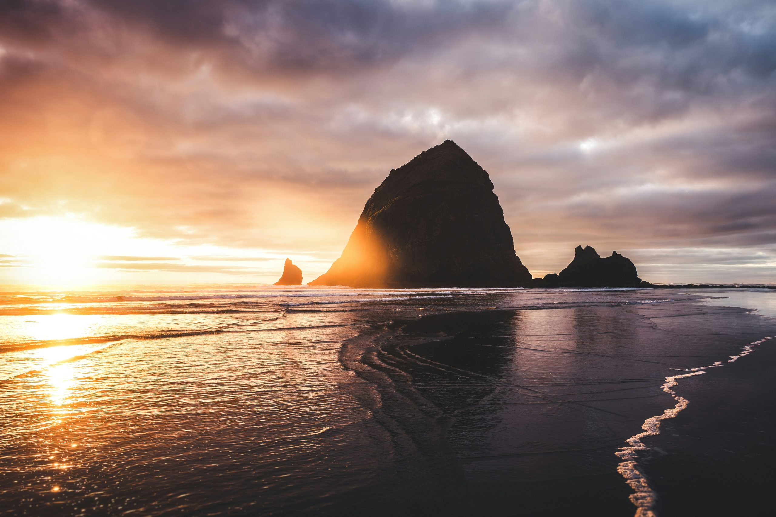 Dramatic sunset over a rocky coastline with wet sand