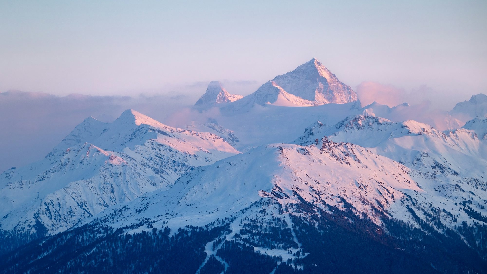 Snow-Covered Mountains Bathed In Soft Pink Sunrise Light