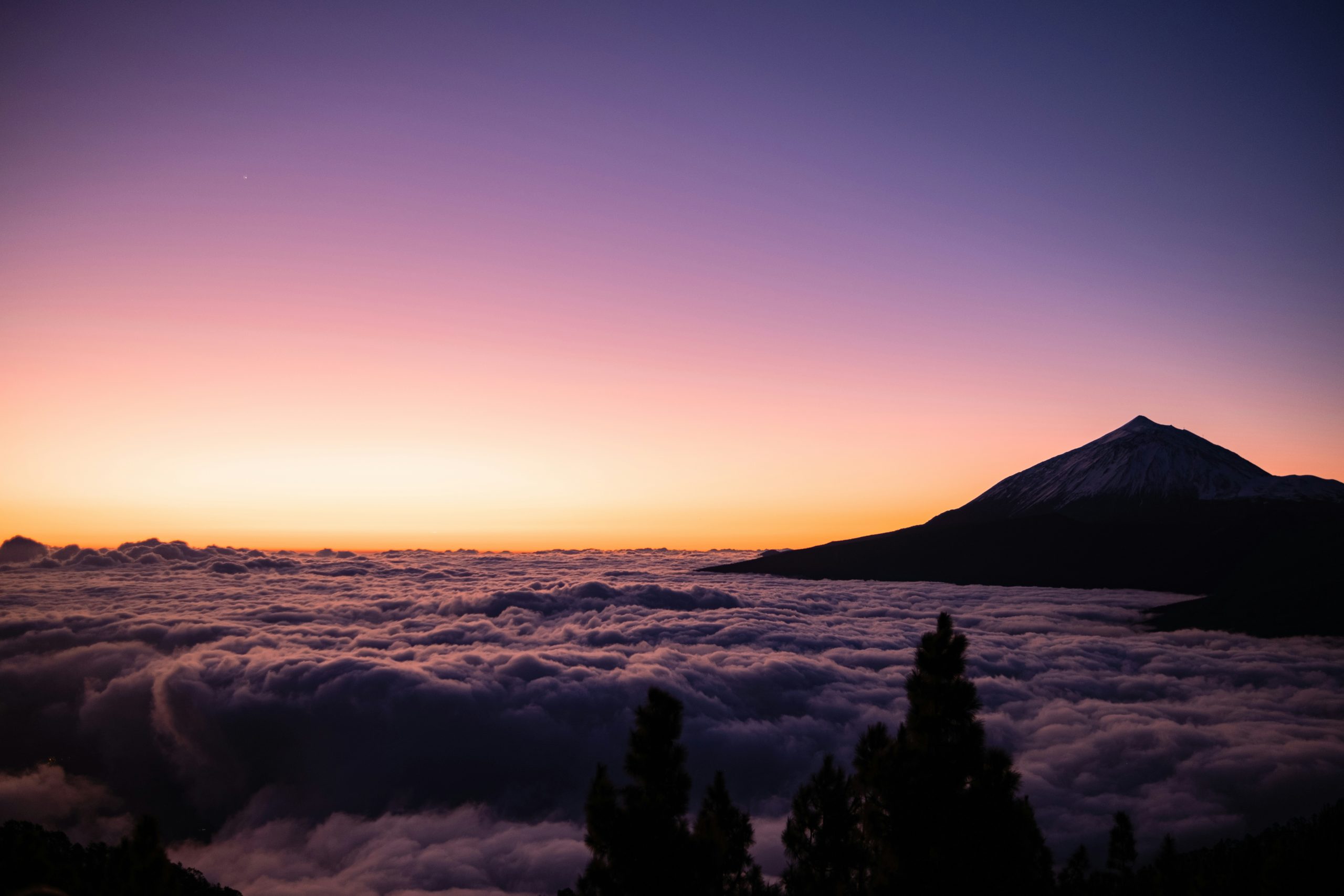 Mountain peak rises above a sea of clouds at sunset