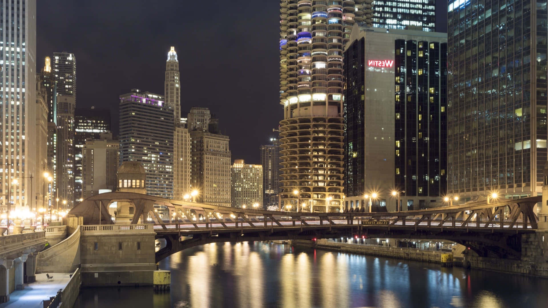 Nighttime city skyline with lit buildings and bridge over water. – Ultra HD Wallpaper