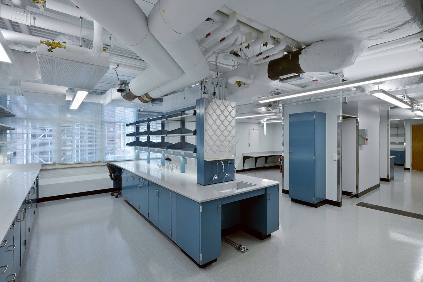 Modern science lab with blue cabinets and exposed ceiling pipes.
