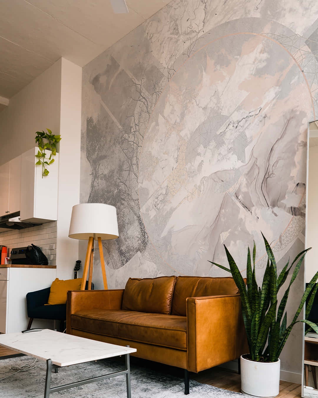 A modern living room with a brown leather sofa, marble wallpaper, and potted plant.
