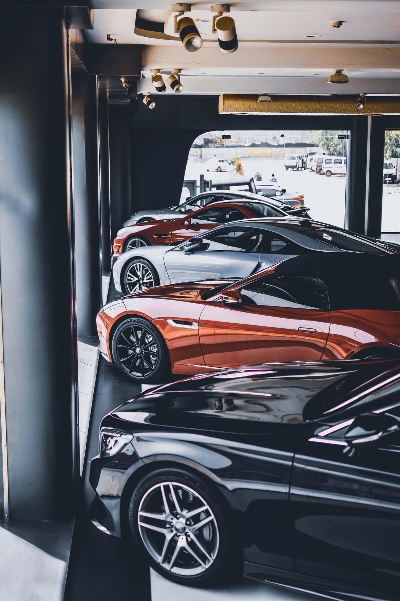 Sleek luxury sports cars in metallic colors displayed in a modern indoor showroom. – Ultra HD Wallpaper