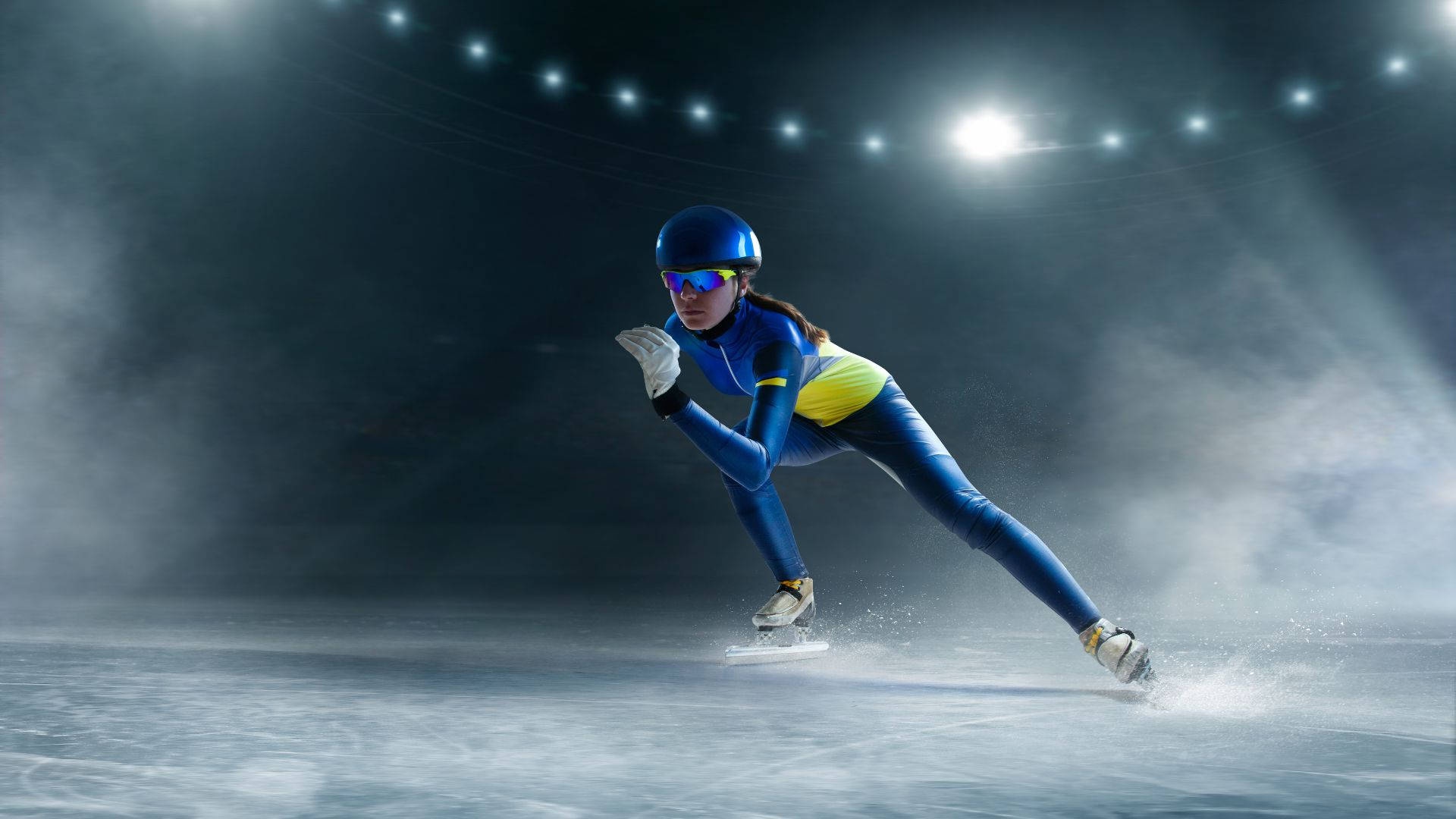 Speed skater in blue and yellow suit gliding on ice under bright lights. – Ultra HD Wallpaper