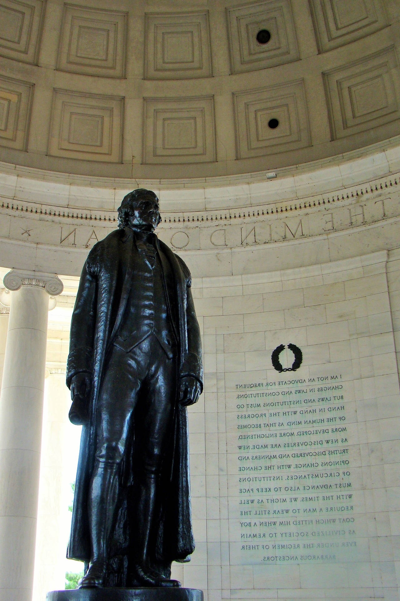 Black bronze statue of a robed man inside a domed marble hall with inscriptions. – Ultra HD Wallpaper