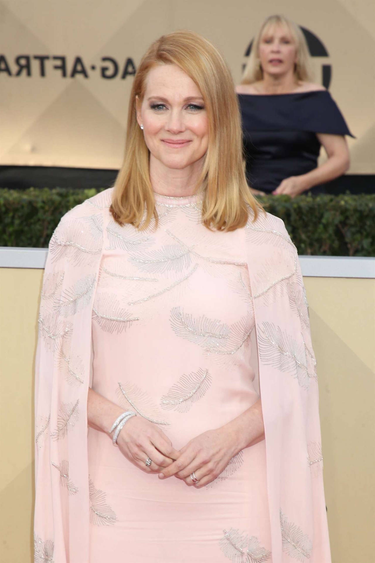 Woman in pink feathered gown smiling at formal event