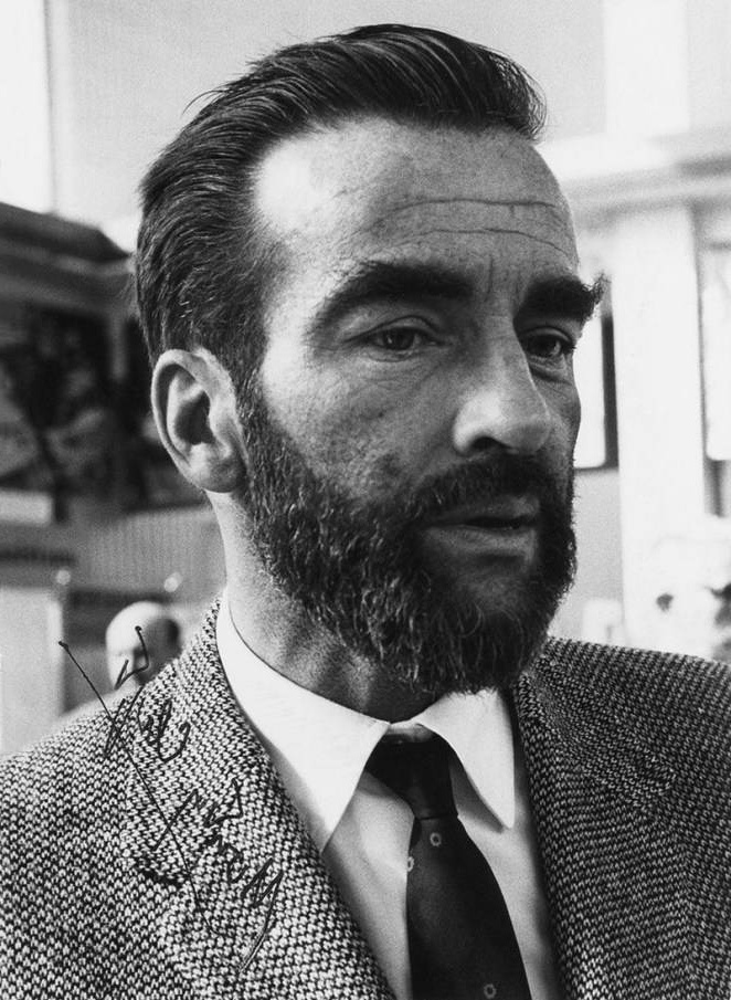 Close-up portrait of a bearded man in a suit and tie with a signature on his jacket. – Ultra HD Wallpaper