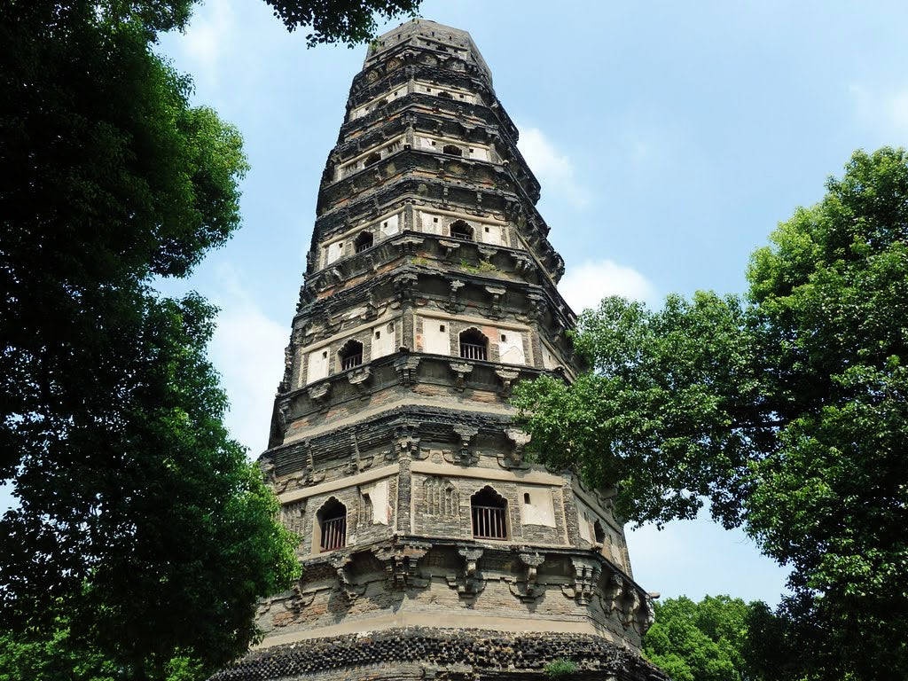 Ancient stone pagoda surrounded by green trees under a blue sky.