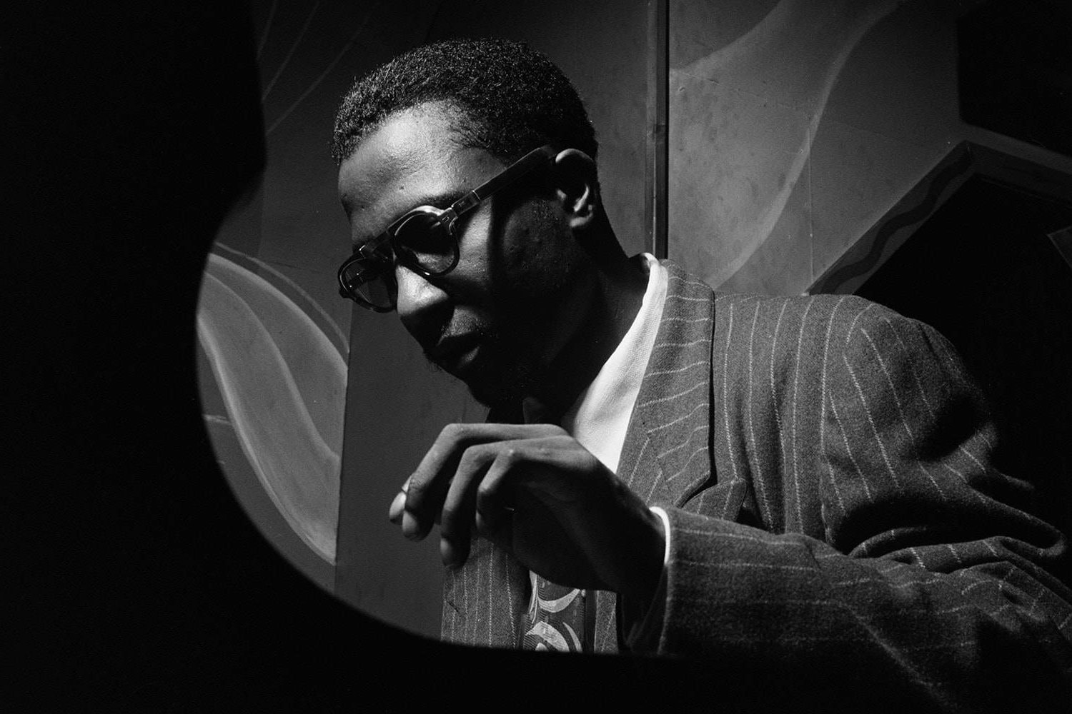 Man in pinstripe suit and glasses viewed through circular window in high contrast black and white. – Ultra HD Wallpaper