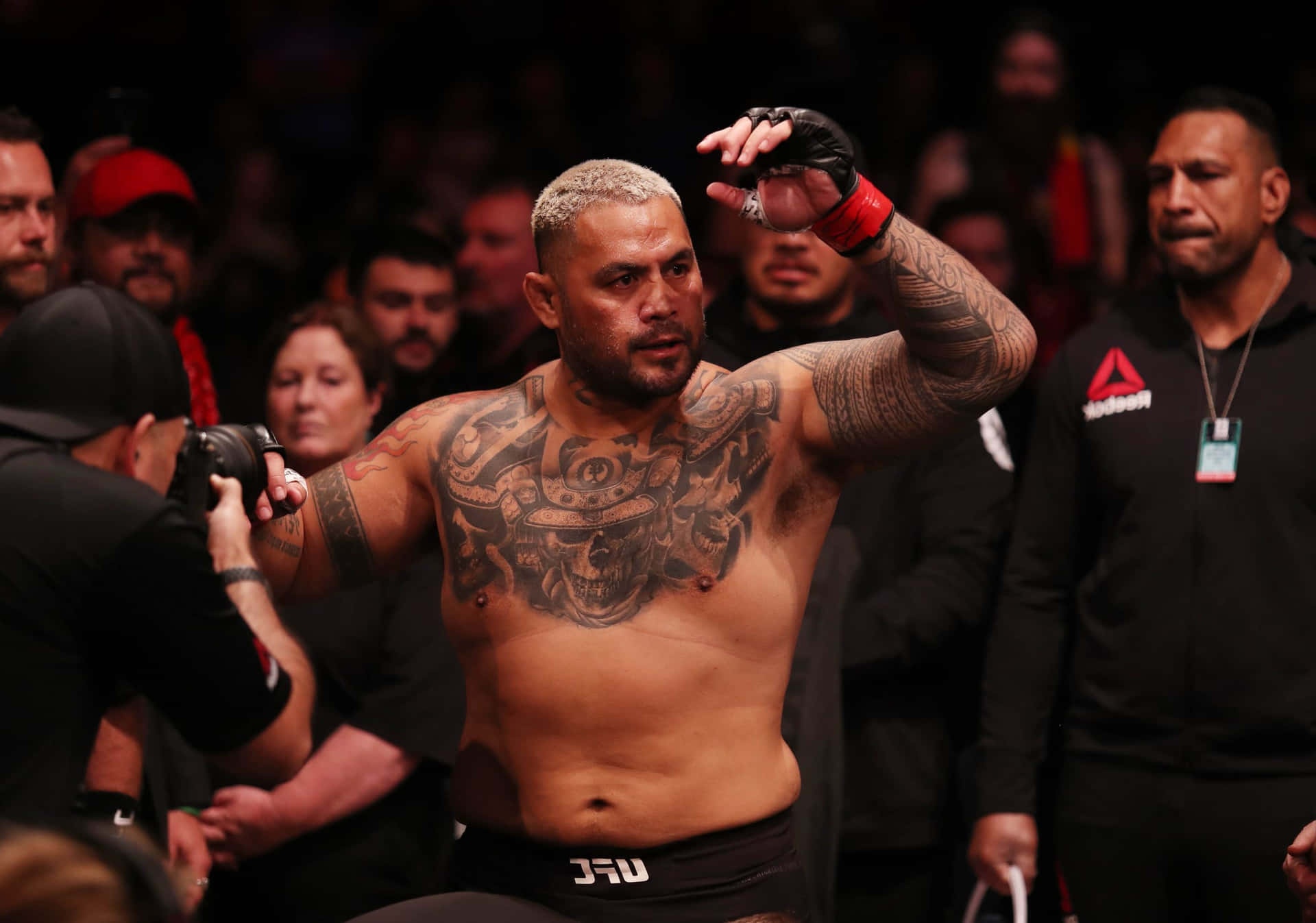 Tattooed MMA fighter celebrating victory in a crowded arena.