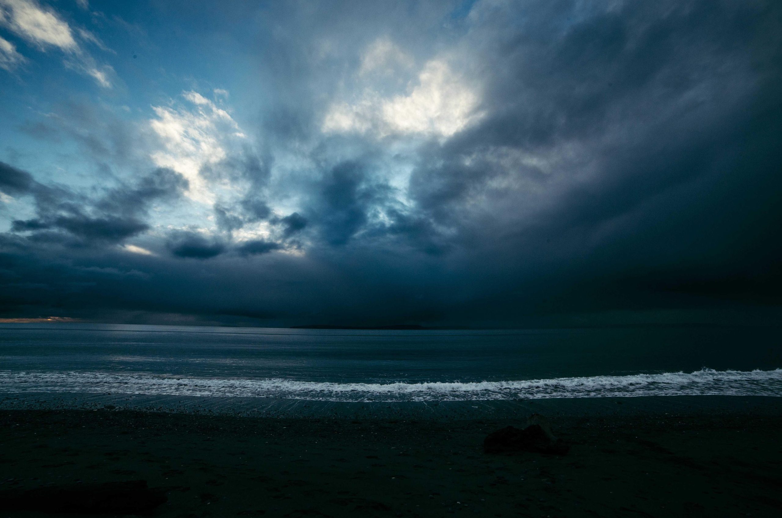 Moody overcast sky above a lone tree on a windswept hill