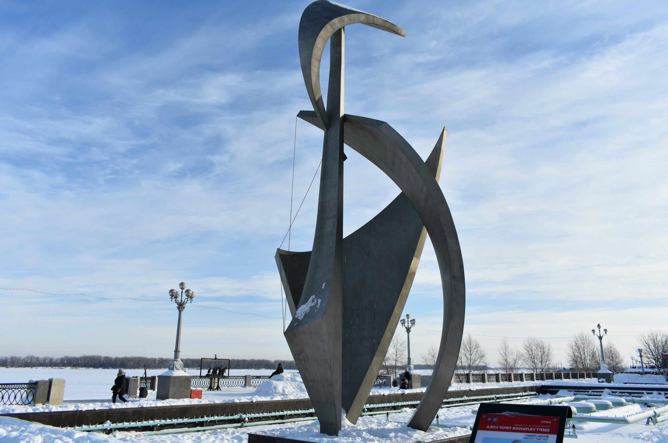 Modern metal sculpture in a snowy park setting.