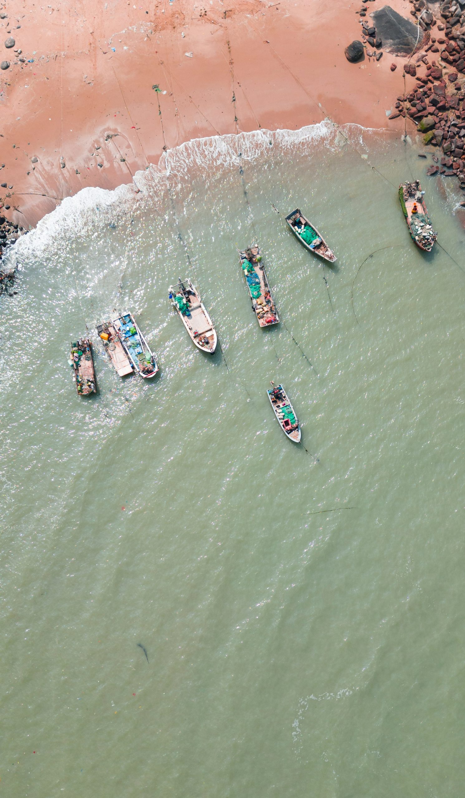 Several fishing boats rest near a sandy shore.