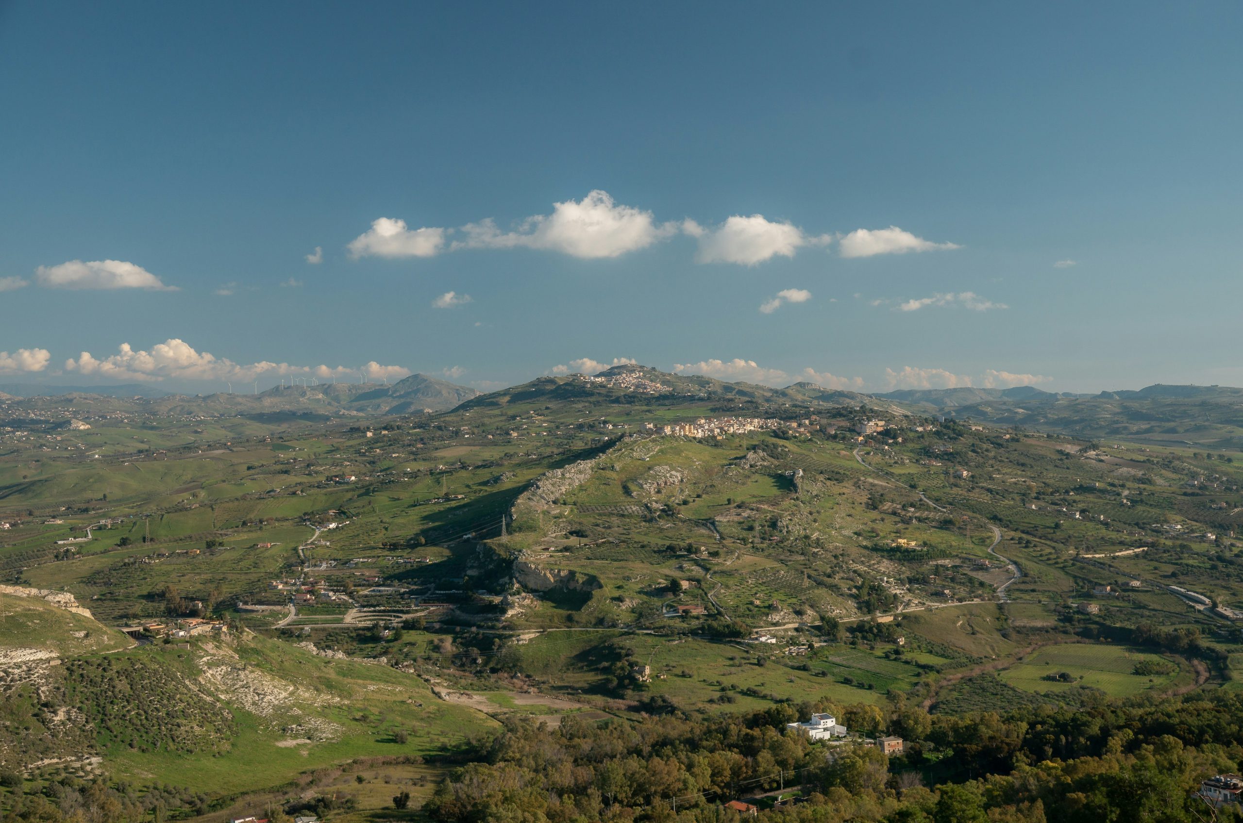A vast green landscape with rolling hills and a town.