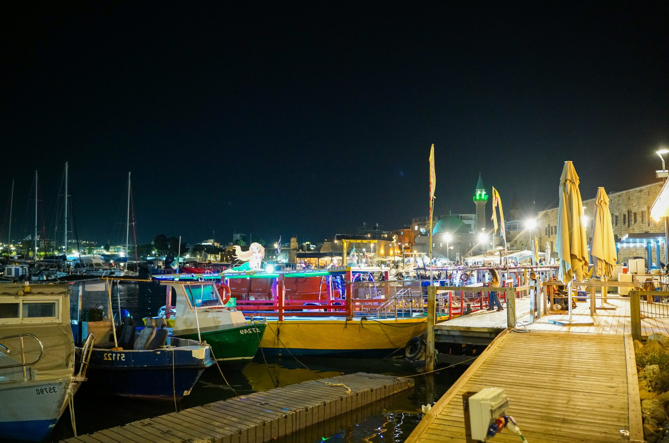 Boats docked at a lively harbor at night