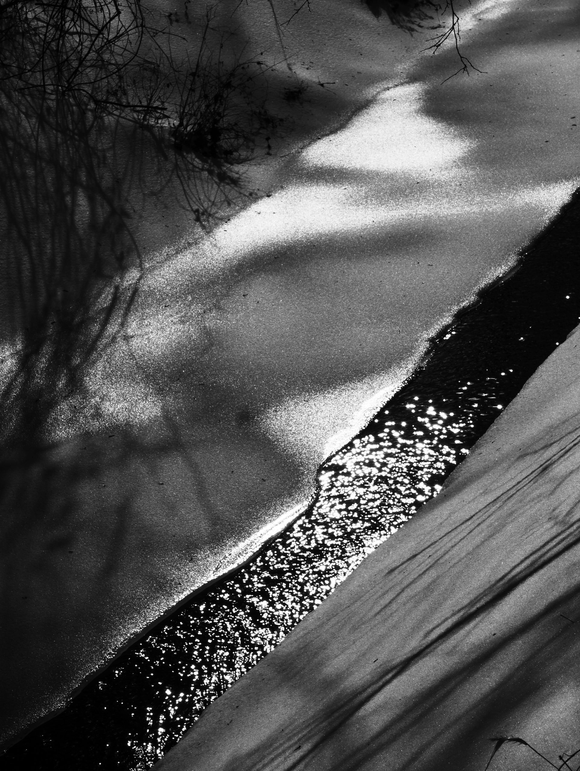Sparkling sunlight on a frozen stream in winter