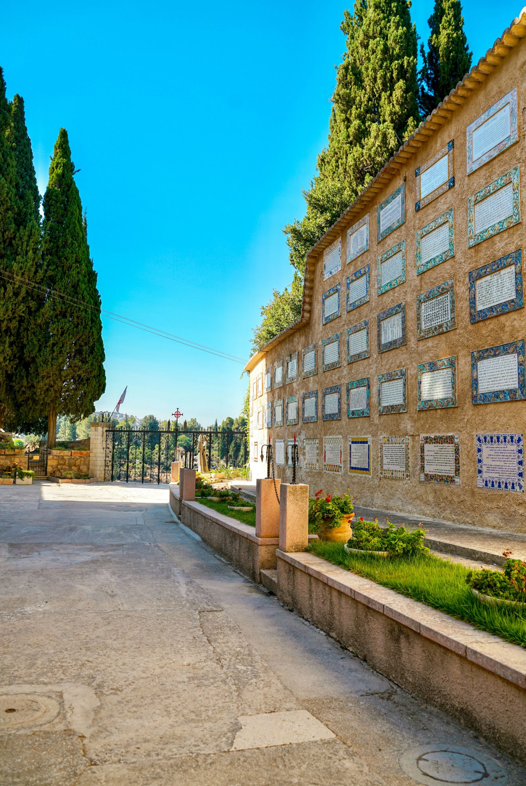 Wall with niches and cypress trees under blue sky