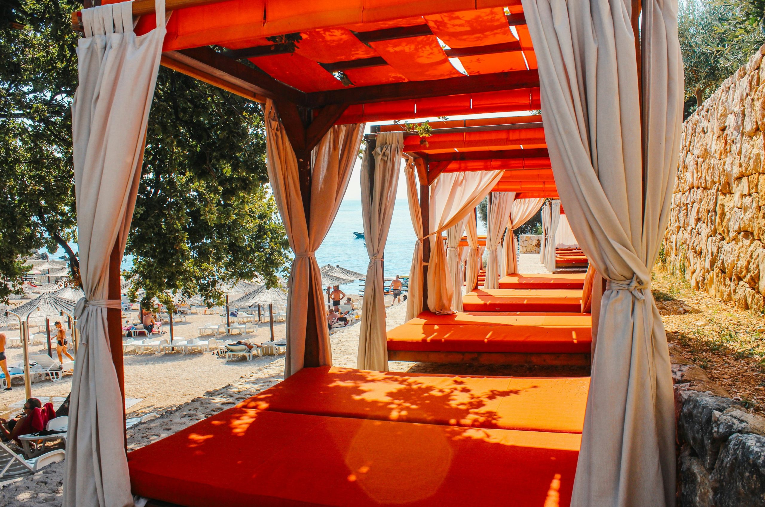 Orange lounge beds with curtains on a sunny beach
