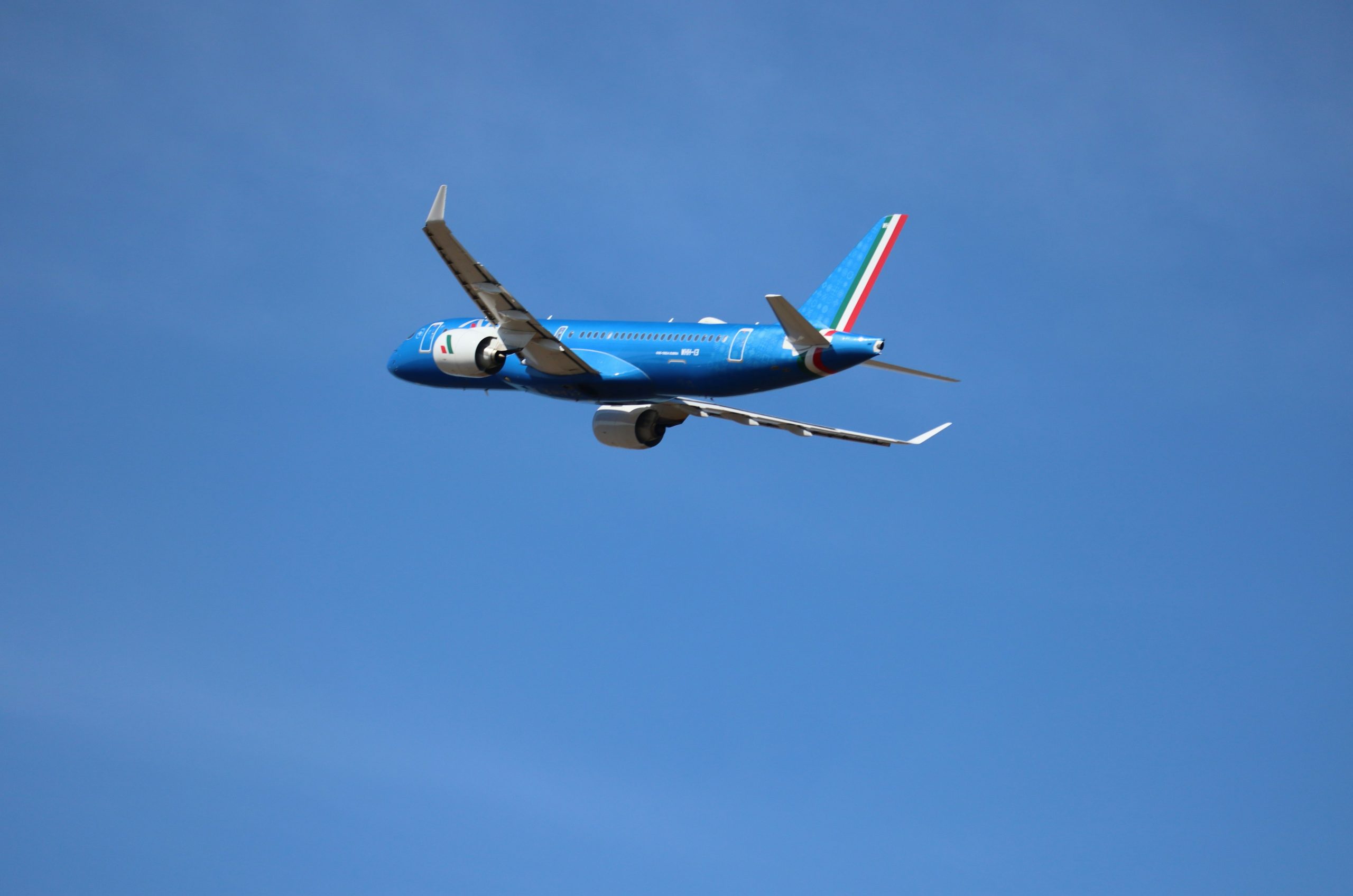 A blue airplane flying in a clear sky