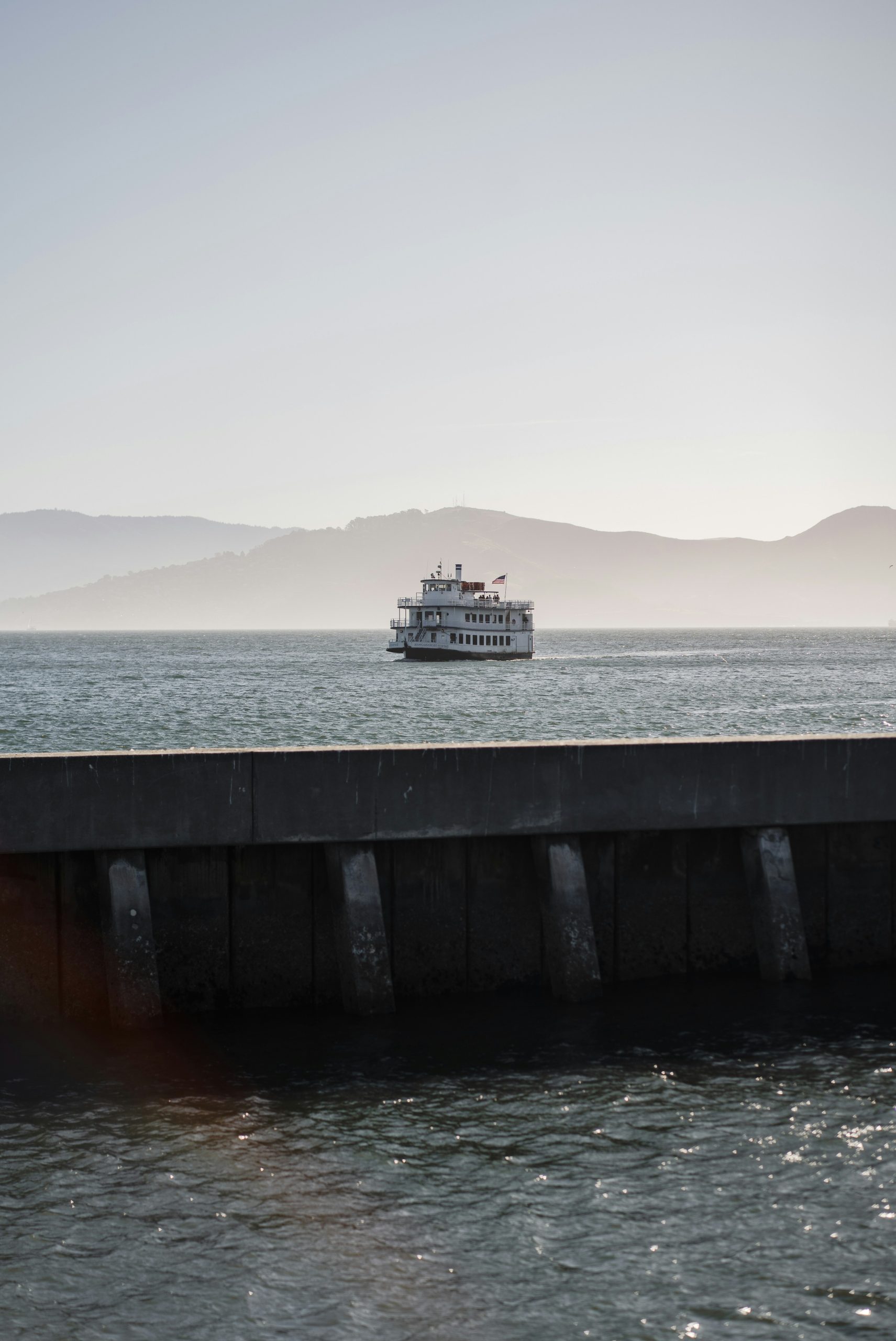 A white boat sails on the water near mountains.