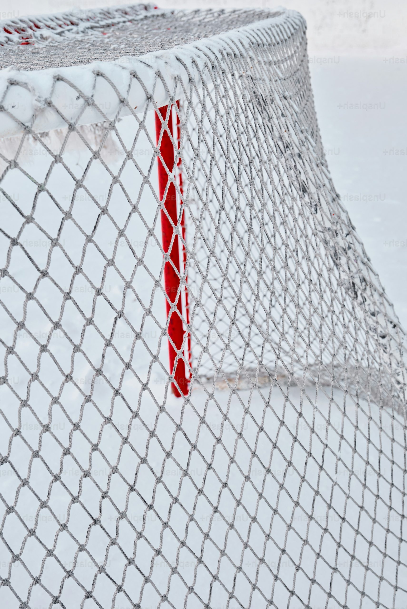 Close-up of a snowy hockey net with red post.