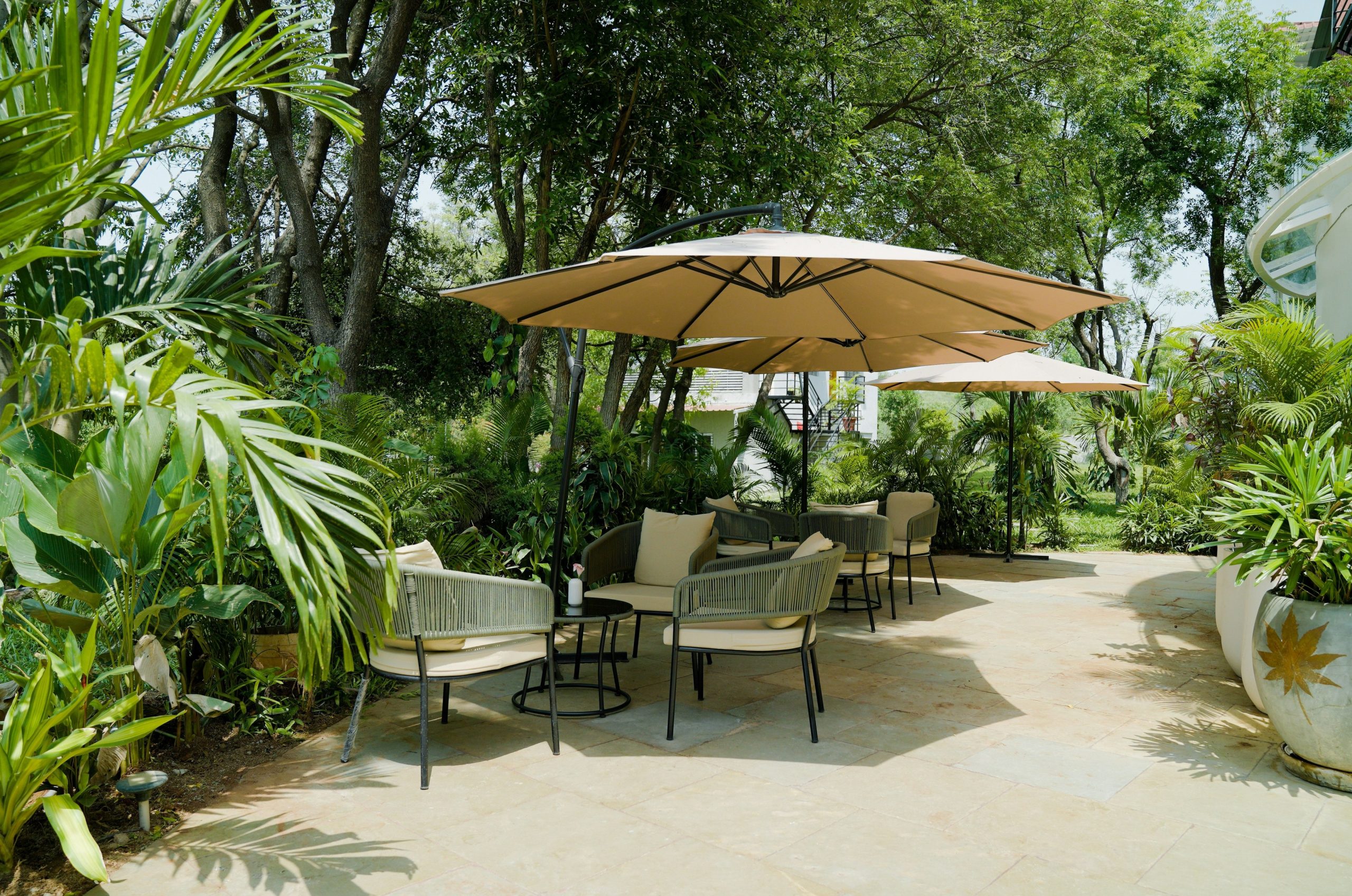 Outdoor seating area with umbrellas and lush greenery.