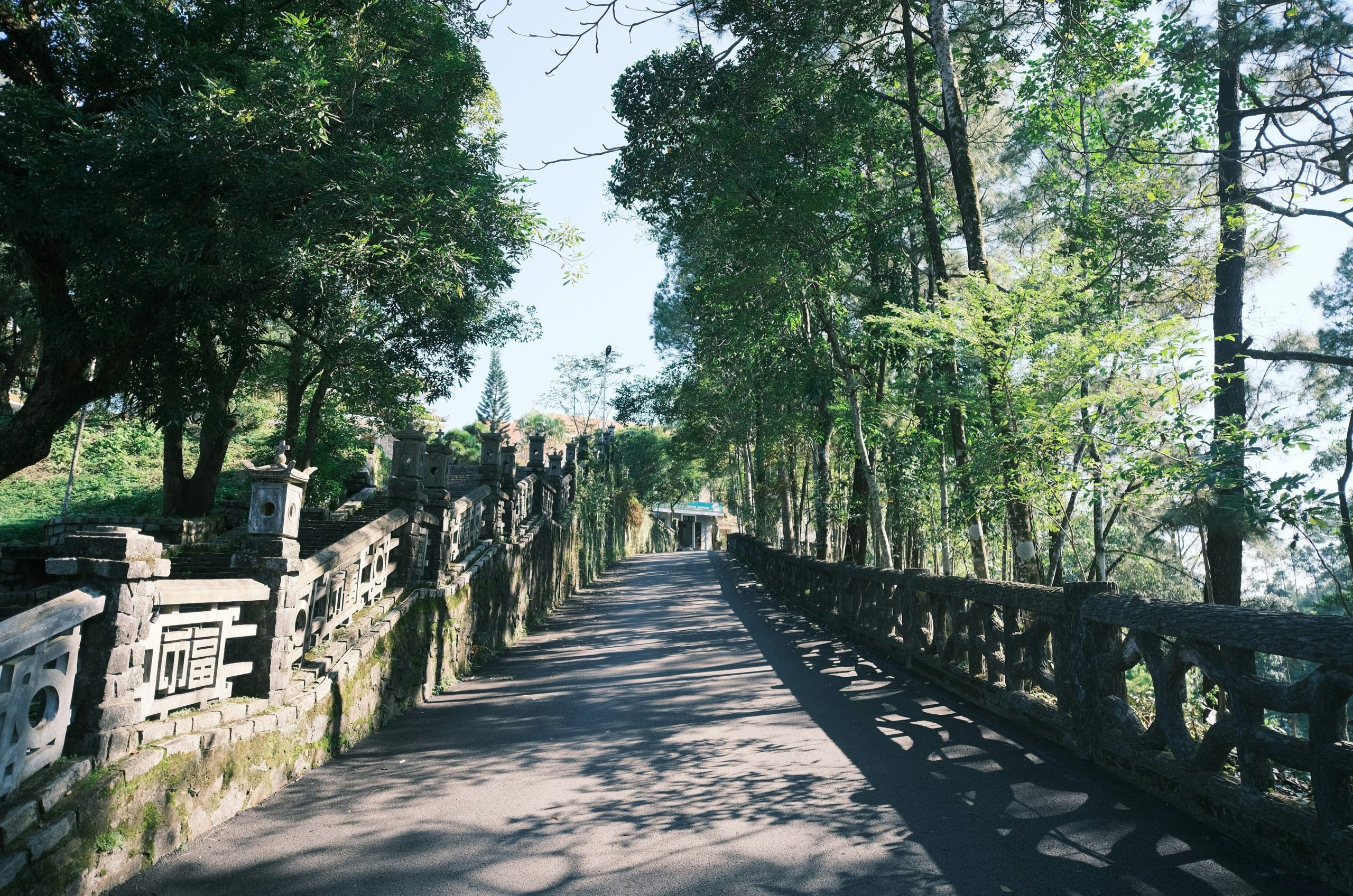 A paved pathway lined with stone railings and trees