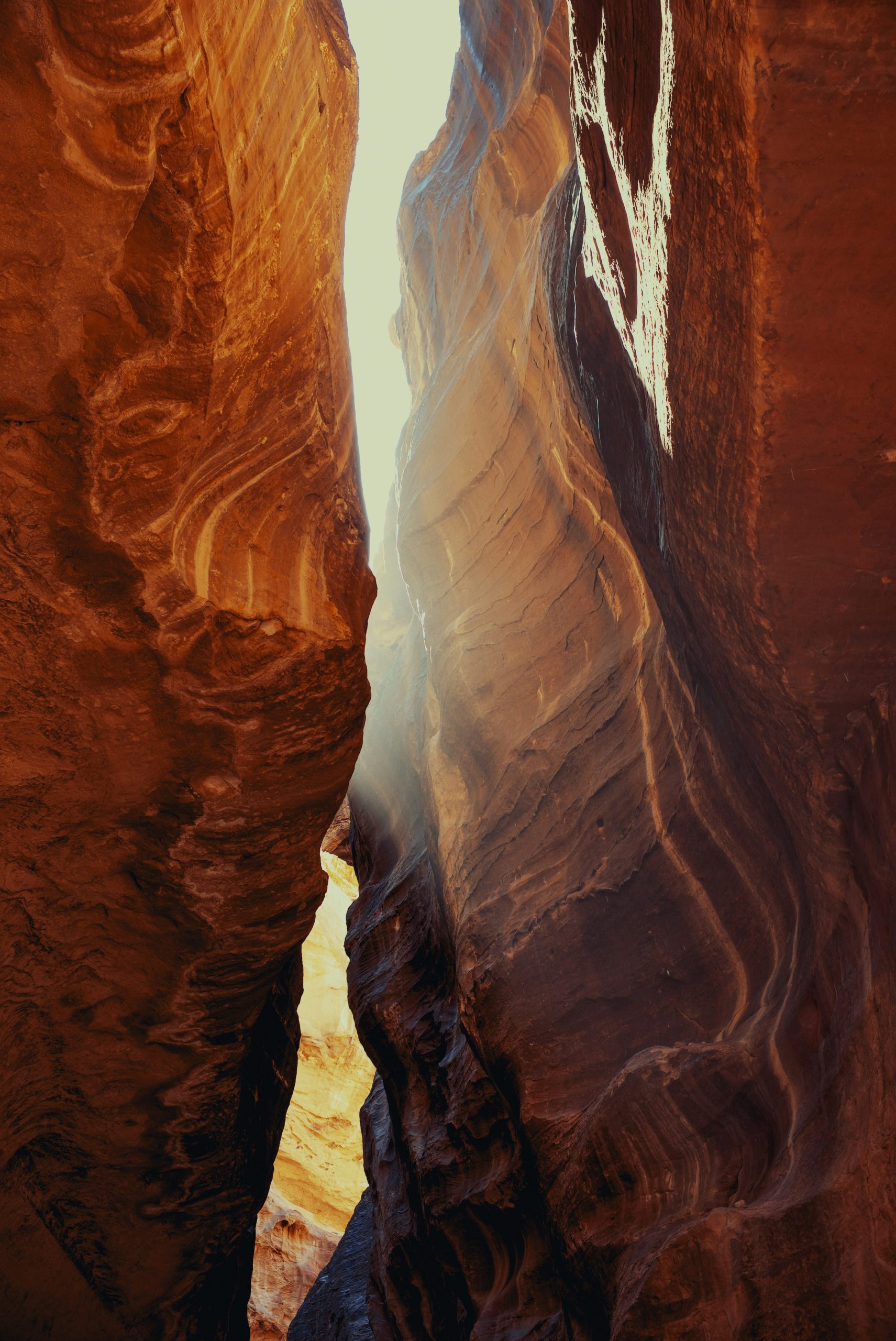 Sunlight streams through a narrow canyon passage.