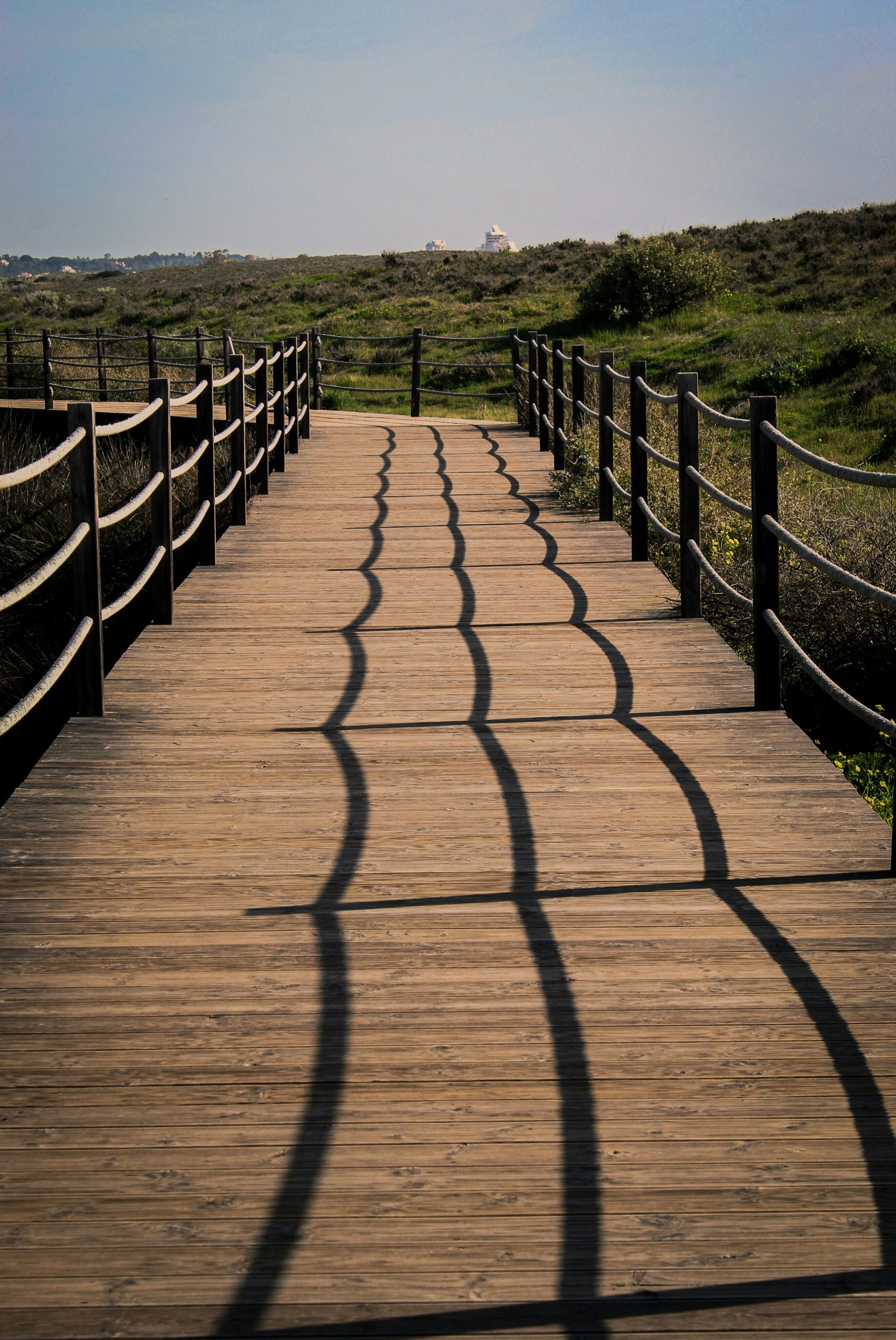 Wooden walkway with rope railings and shadows