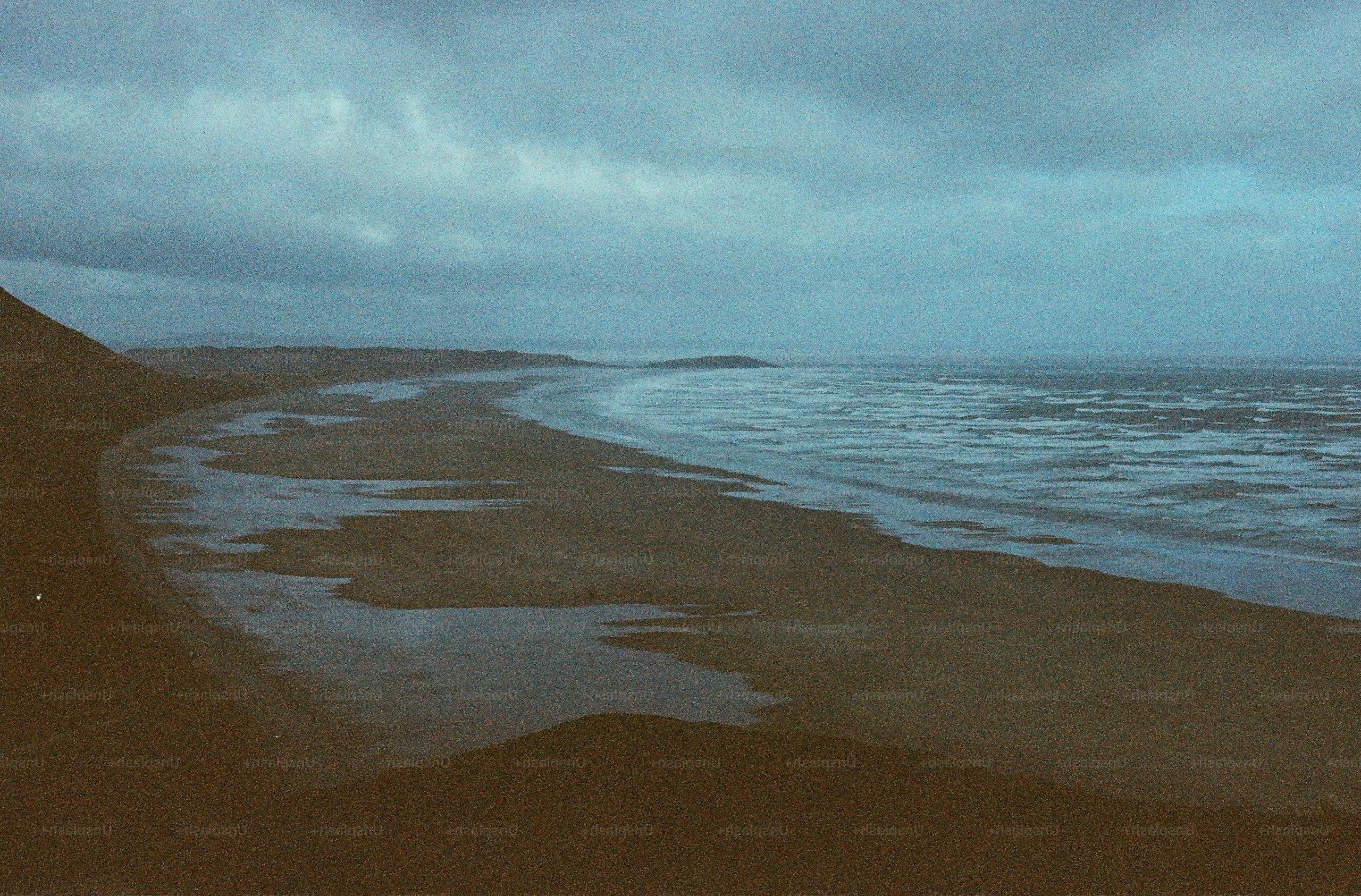 A wide, empty beach under a cloudy sky