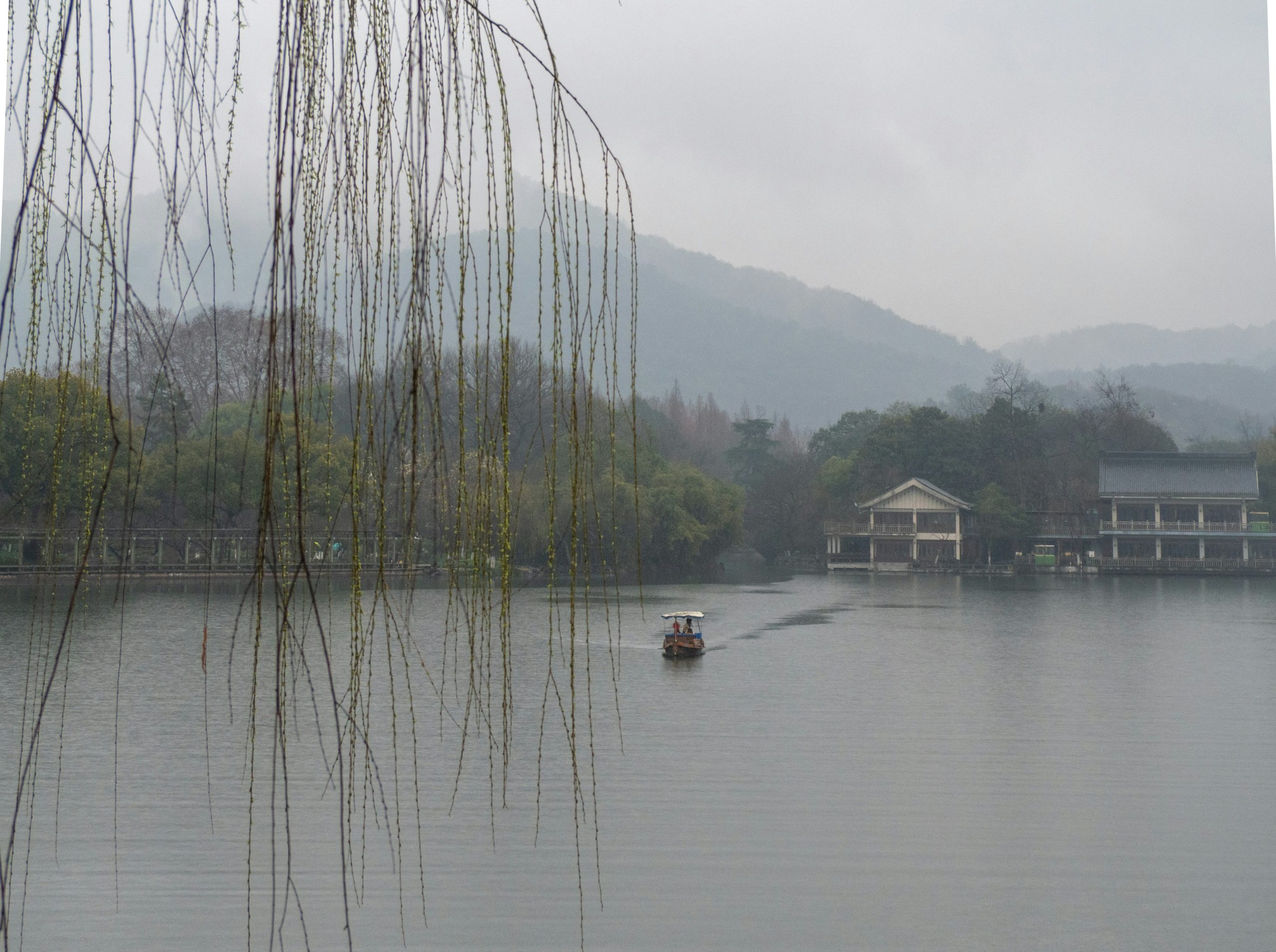 A boat sails on a misty lake with distant hills.