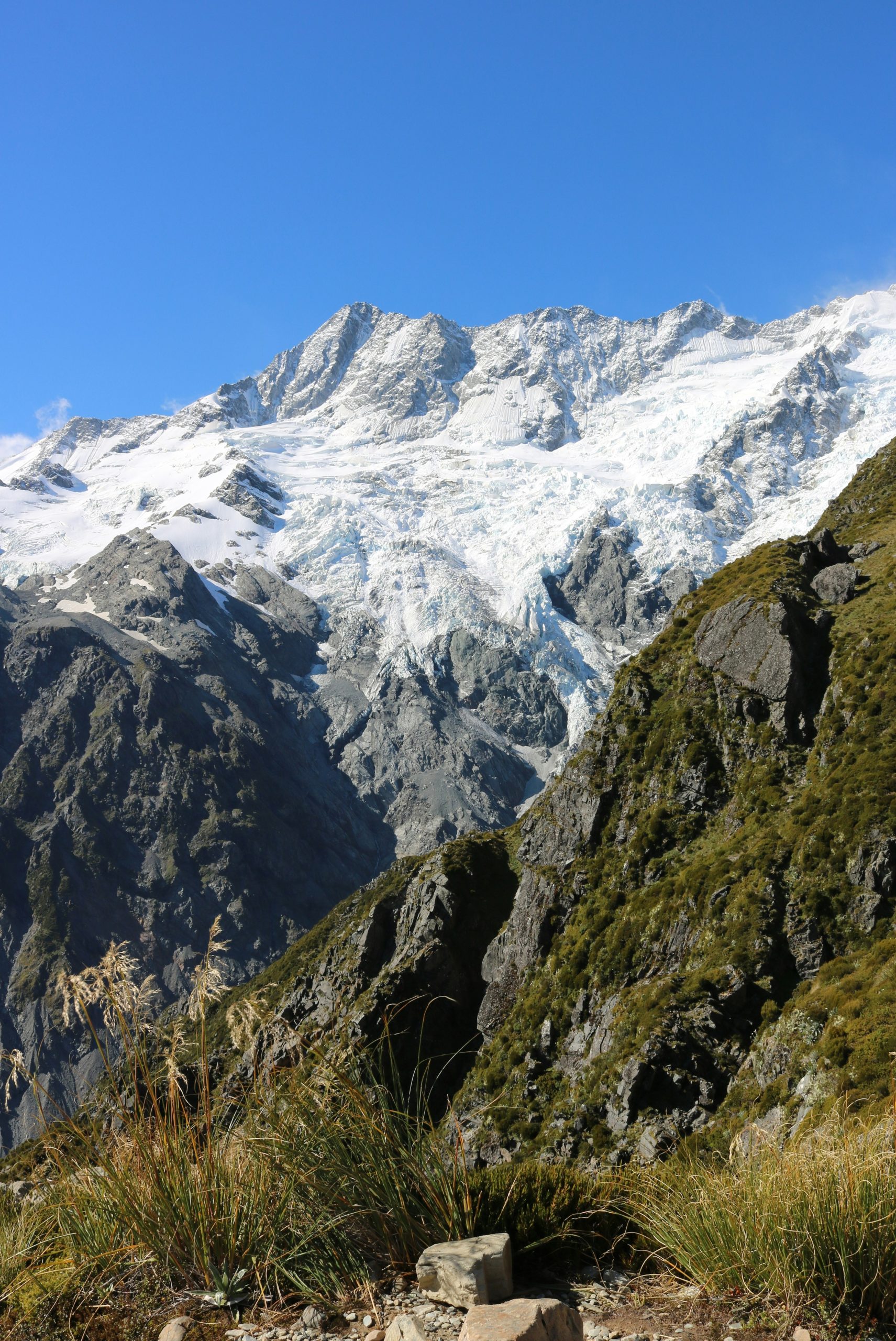 Snow-capped mountains with rocky slopes and green grass