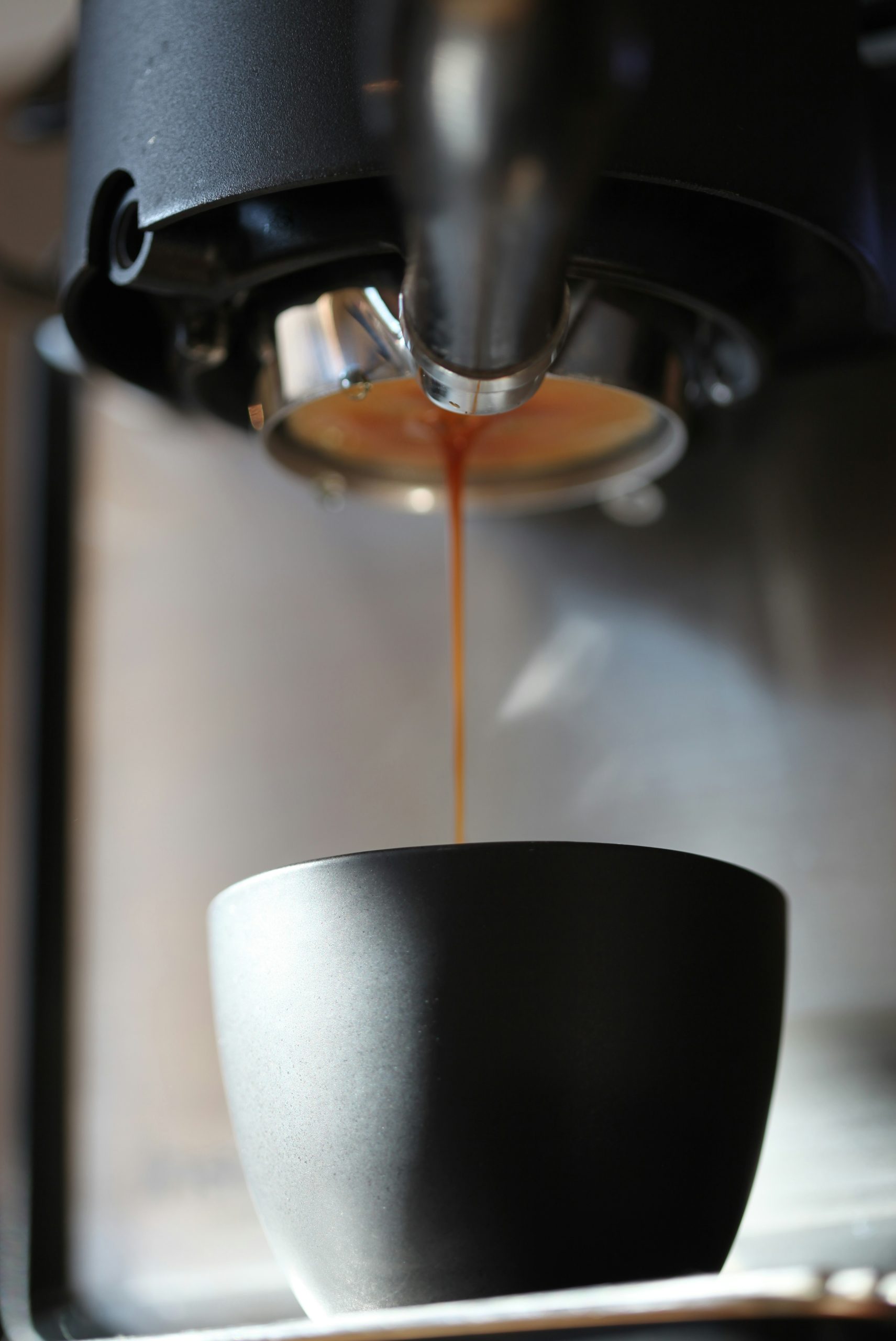 Espresso pouring into a dark cup from machine
