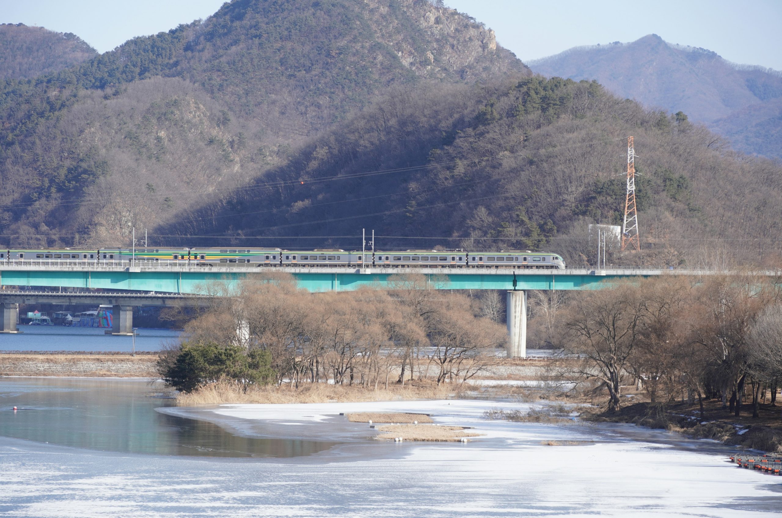Train crossing a bridge over a frozen river.
