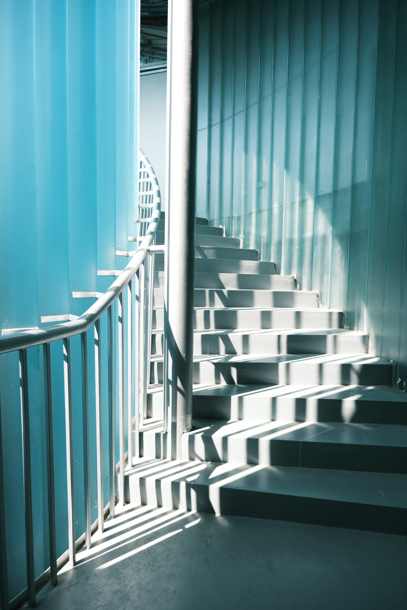 Sunlight streams down a modern spiral staircase